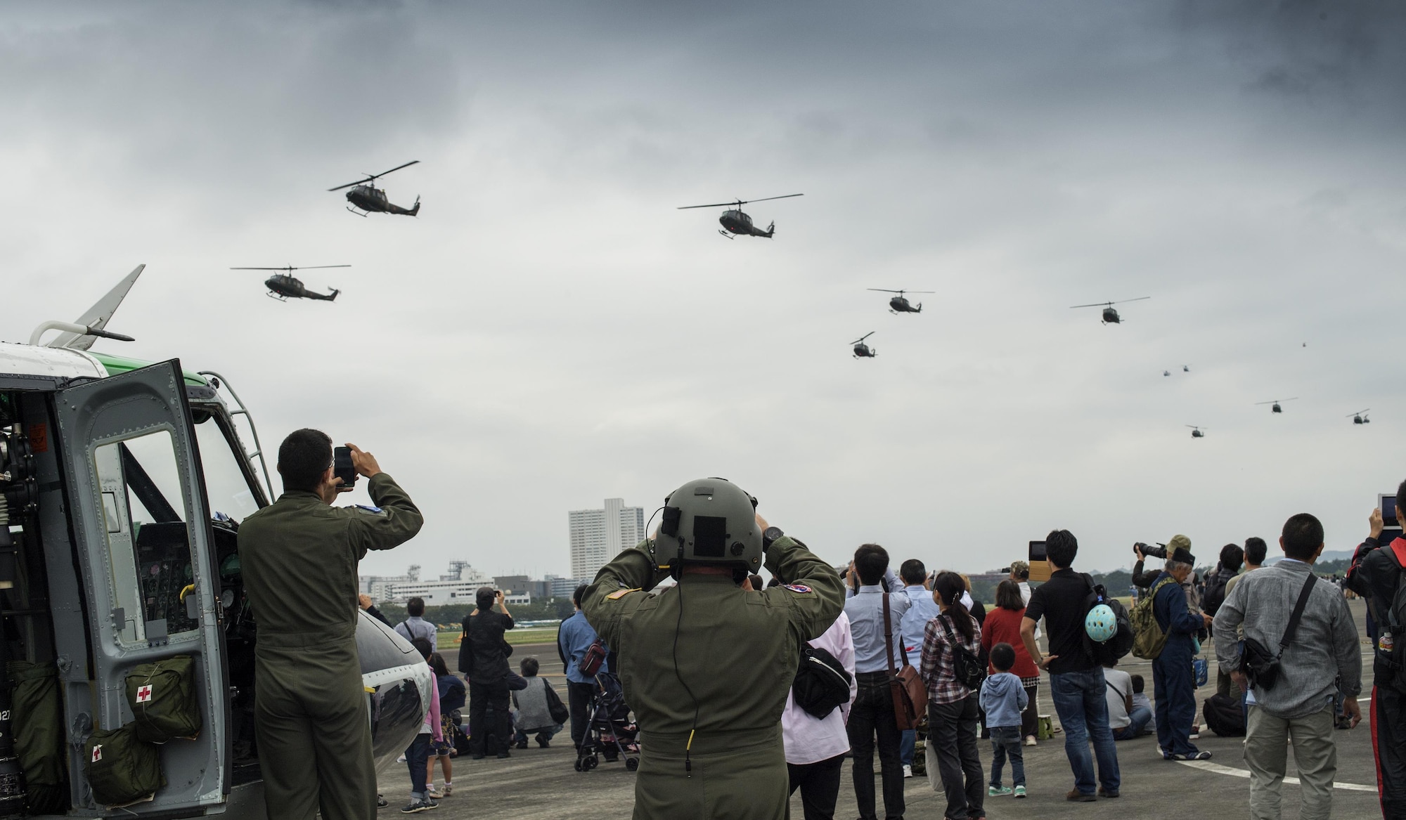 U.S. Air Force Capt. Vicente Vasquez, left, 459th Airlift Squadron UH-1N pilot, and Tech. Sgt. David Jacob, 459th AS flight engineer, watch a Japan Ground Self-Defense Force UH1-J formation flight demonstration during the 43rd Anniversary Event of Japan Ground Self-Defense Force Camp Tachikawa at JGSDF Camp Tachikawa, Japan, Oct. 1, 2016. JGSDF UH-1Js assigned to Eastern Army Helicopter demonstrated flight formations, hoist techniques and disaster relief procedures with first responders. Service members with the 459th Airlift Squadron from Yokota Air Base and Army Aviation Battalion from Camp Zama participated in the festival. (U.S. Air Force photo by Yasuo Osakabe/Released)