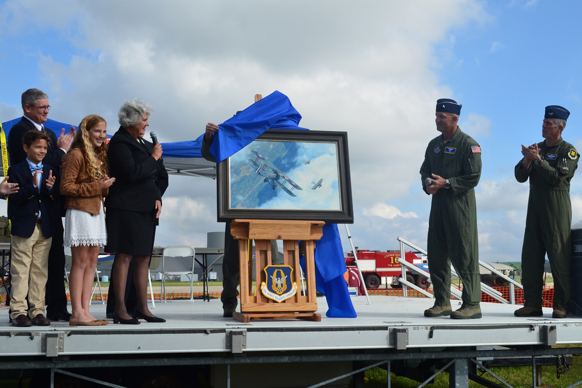 Susan Mozena speaks prior to the unveiling of a painting depicting former Reservist First Lieutenant Charles d'Olive, 93rd Pursuit Squadron, in the cockpit of his French-built Spad XIII pursuit aircraft engaging five German aircraft during World War I, Wright Field, Dayton Ohio, Oct. 1, 2016. The Mozena family were onstage during the unveiling. (U.S. Air Force Tech. Sgt. Pam Ives/Released)