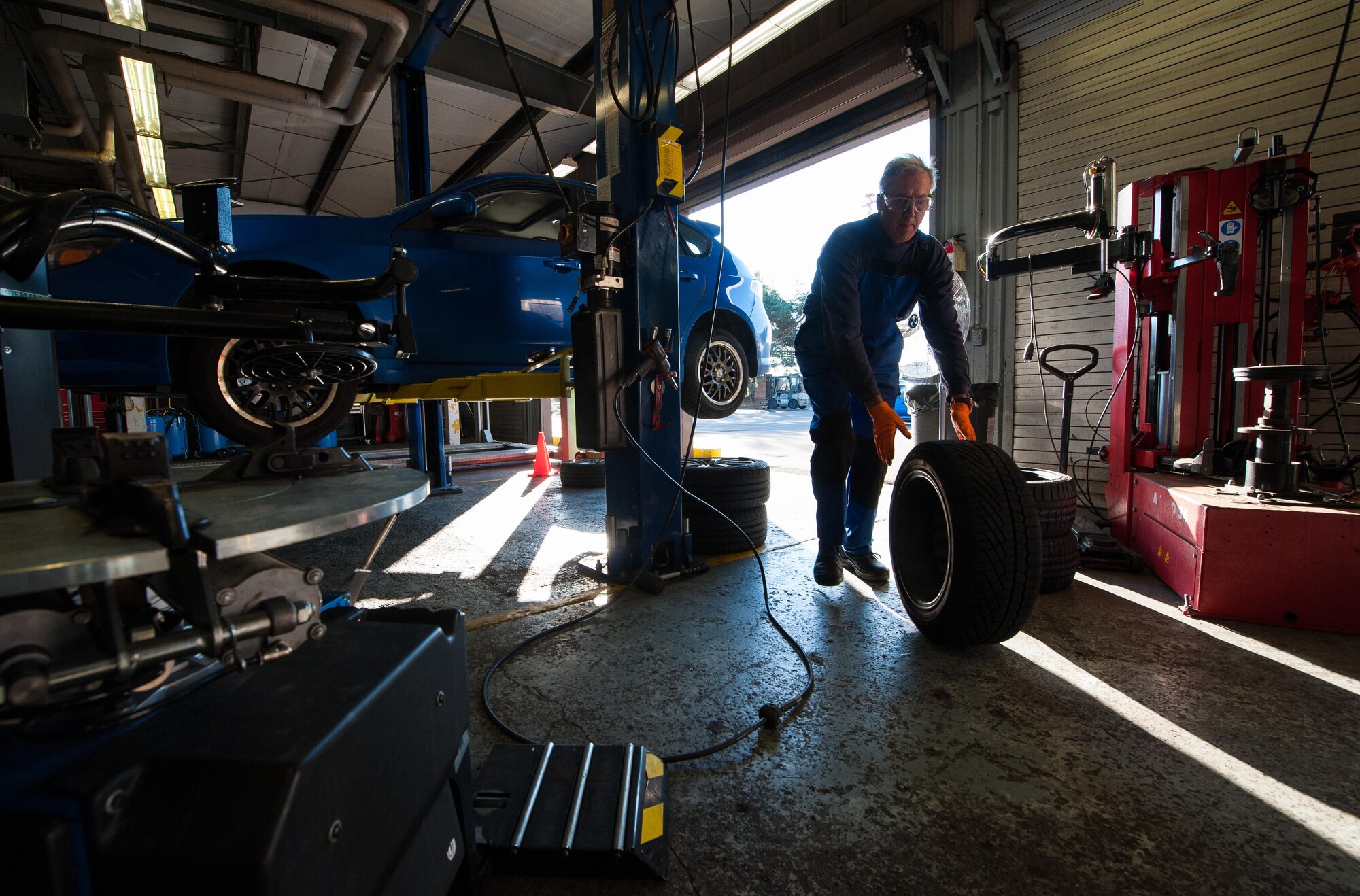 Retired Air Force Master Sgt. Greg Hermann, 86th Force Support Squadron tire technician at the Auto Hobby Shop at Ramstein Air Base, Germany, rolls one of his customer’s tires in for a tire inspection Oct. 5, 2016. Hermann mans the tire shop alone, and changes an average of 40-50 tires every day. (U.S. Air Force photo by Airman 1st Class Lane T. Plummer)