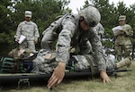 Pfc. Luke Deboer, a candidate for the Expert Field Medical Badge (EFMB), prepares a simulated casualty for movement during EFMB qualification testing, which was held at Fort Drum, N.Y. from Aug. 20 to Sept. 2. Out of a field of 239 medics, 29 bested a 12-mile ruck march, a written test, simulated combat training lanes and other challenges to earn the EFMB. 