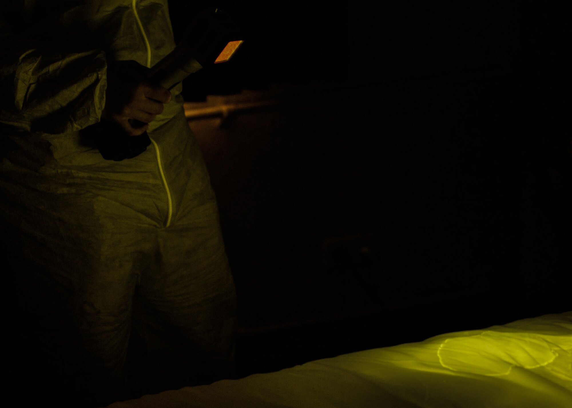 An Air Force Office of Special Investigations 4th Field Investigations Squadron agent utilizes an alternate light source during a mock crime scene at Ramstein Air Base, Germany, Oct. 6, 2016. Agents may select from six different light sources to search for biological fluids undetectable to the naked eye. The 4th FIS facilitate surprise mock crime scenes for six units biannually within U.S Air Forces in Europe.  (U.S. Air Force photo by Senior Airman Nesha Humes)