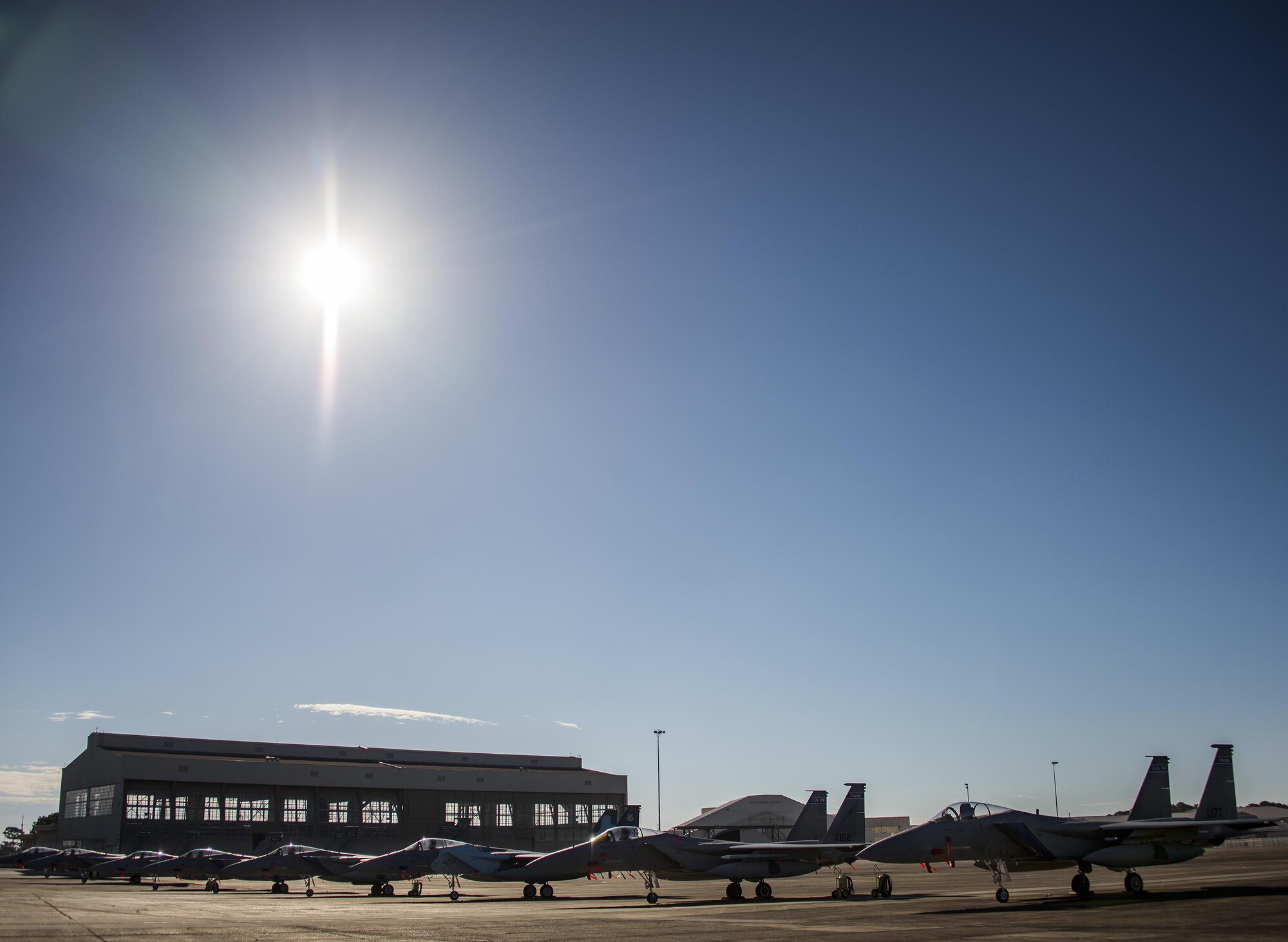 Clear skies and bright sun shines down on a row of 125th Fighter Wing F-15s from Jacksonville Fla., on the Eglin Air Force Base flightline Oct. 7.  The Air National Guard unit sent 15 aircraft to ride out Hurricane Matthew here. The Marine Fighter Attack Training Squadron-501 sent 10 F-35Bs from South Carolina to the base for sheltering as well. The 96th Aircraft Maintenance Squadron's F-15 unit and the Navy's Strike Fighter Squadron 101 provided support to the transient aircraft. (U.S. Air Force photo/Samuel King Jr.)