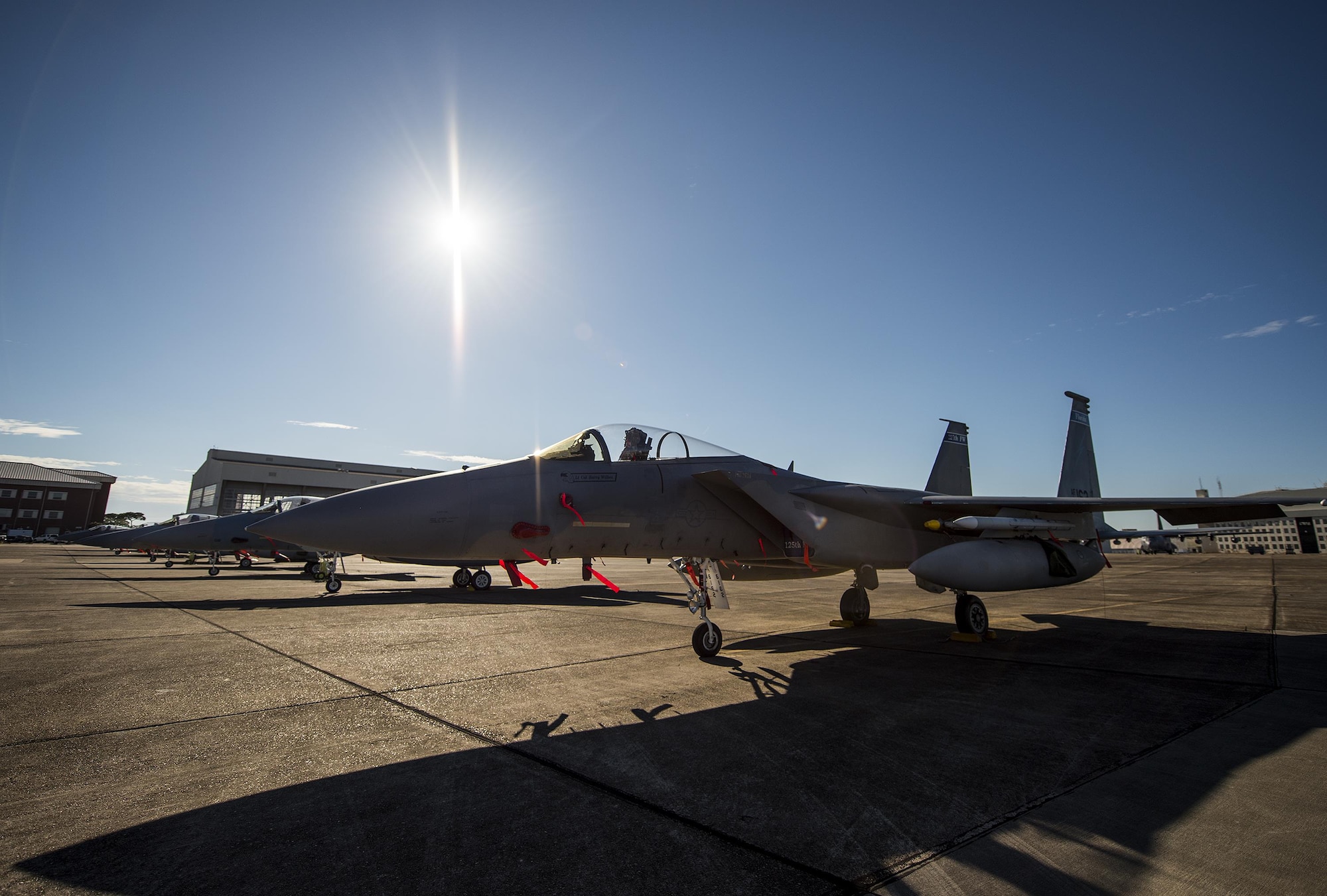 Clear skies and bright sun shines down on a row of 125th Fighter Wing F-15s from Jacksonville Fla., on the Eglin Air Force Base flightline Oct. 7.  The Air National Guard unit sent 15 aircraft to ride out Hurricane Matthew here. The Marine Fighter Attack Training Squadron-501 sent 10 F-35Bs from South Carolina to the base for sheltering as well.  The 96th Aircraft Maintenance Squadron's F-15 unit and the Navy's Strike Fighter Squadron 101 provided support to the transient aircraft. (U.S. Air Force photo/Samuel King Jr.)