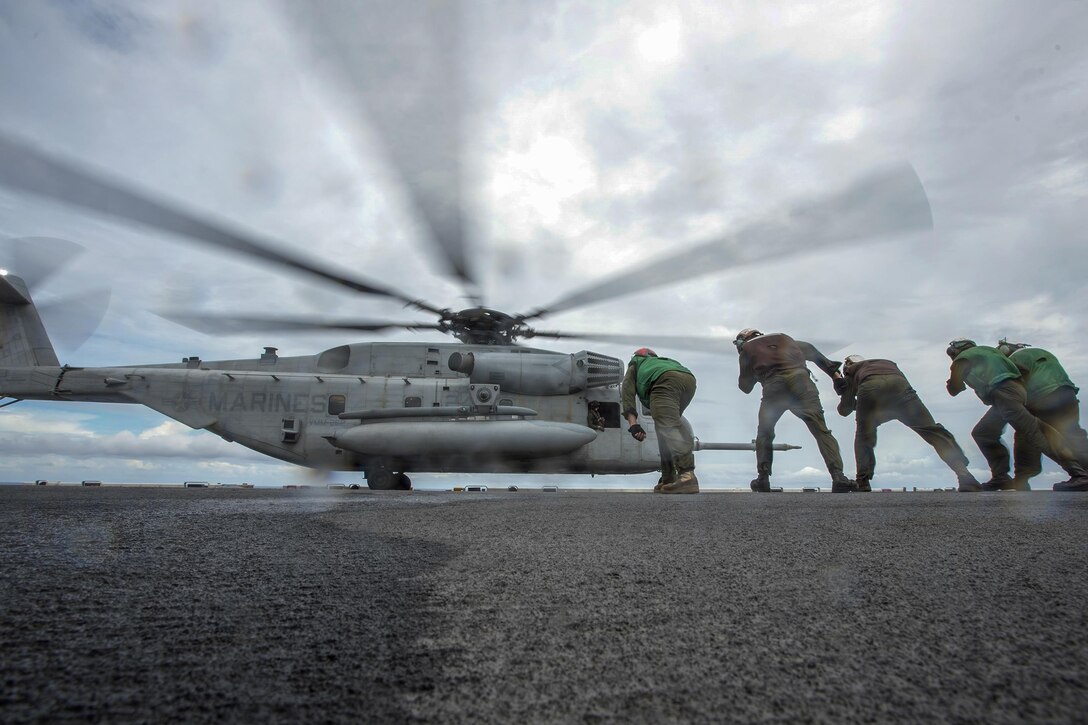Marines lean into the rotor wash of a CH-53E Super Stallion as it takes off from the flight deck of the USS Bonhomme Richard in the South China Sea, Oct. 6, 2016. The amphibious assault ship is supporting security and stability in the Indo-Asia-Pacific region. Navy photo by Petty Officer 2nd Class Diana Quinlan