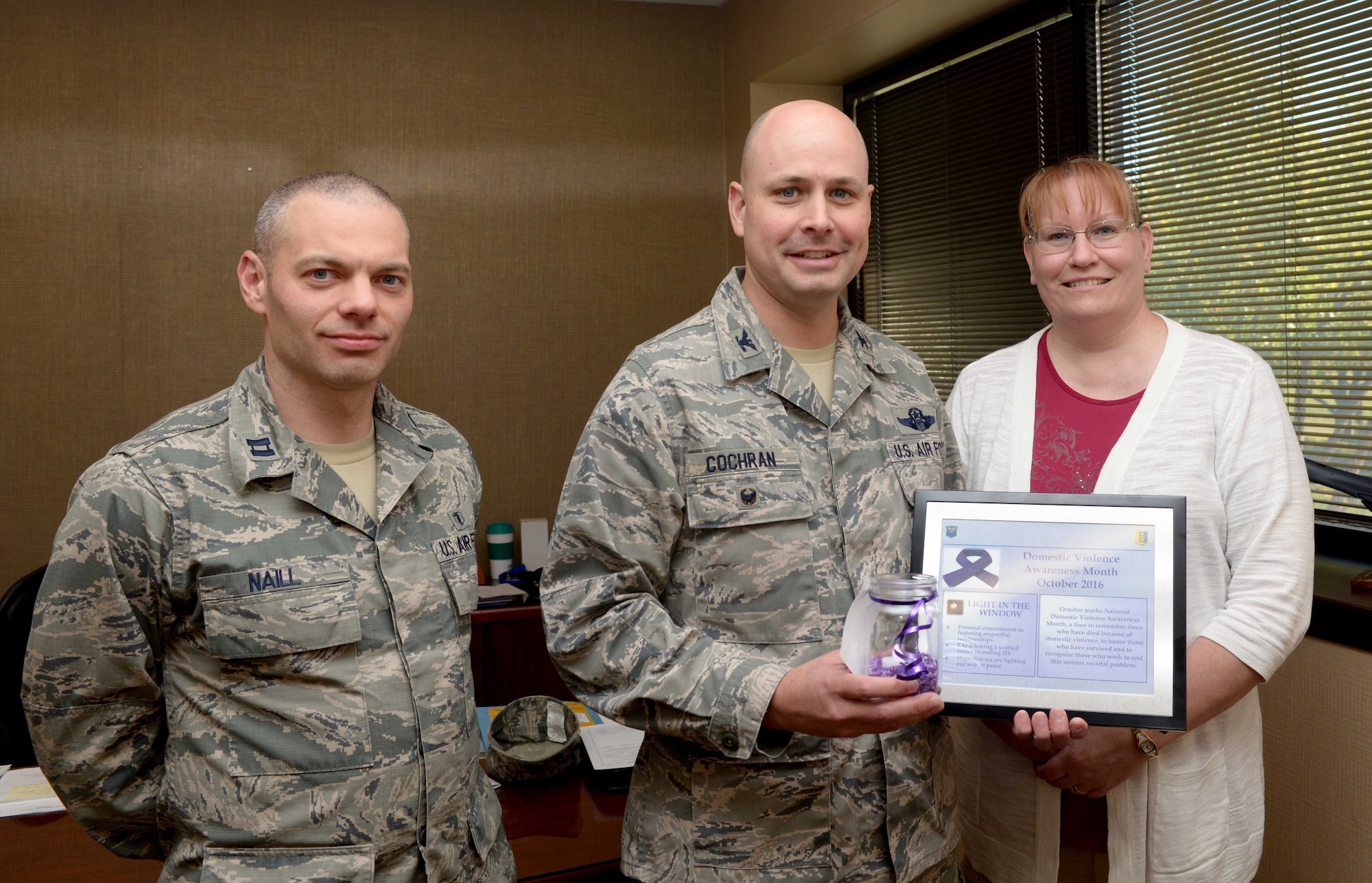 Kimberly Kohler, a family advocacy outreach manager assigned to the 28th Medical Group, right, and Capt. Timothy Naill, a family advocacy officer assigned to the 28th MDG, left, present Col. Bradley Cochran, vice commander of the 28th Bomb Wing, center, with a candle as a part of Domestic Violence Awareness Month at Ellsworth Air Force Base, S.D., Sept. 26, 2016. October is National Domestic Violence Awareness Month, a time to remember those who have lost their lives to domestic violence and honor those who have survived. (U.S. Air Force photo by Airman 1st Class Donald C. Knechtel)