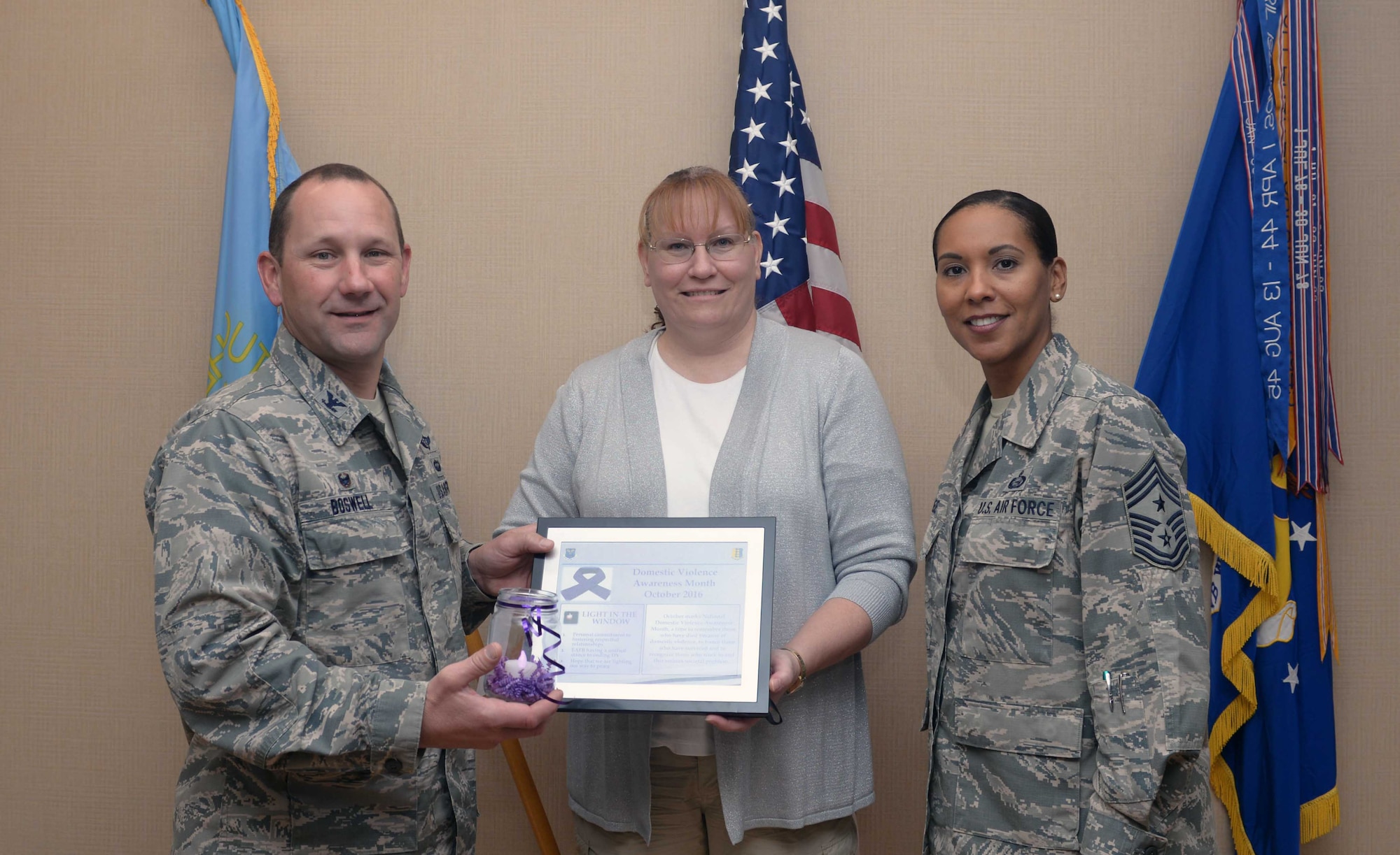 Kimberly Kohler, a family advocacy outreach manager assigned to the 28th Medical Group, center, presents Col. Gentry Boswell, the commander of the 28th Bomb Wing, left, and Chief Master Sgt. Sonia Lee, the command chief of the 28th Bomb Wing, right, with a candle as a part of Domestic Violence Awareness Month at Ellsworth Air Force Base, S.D., Sept. 27, 2016. The candle is intended to serve as a beacon that represents hope and a safety for those who are in distress as well as help remember lost loved ones. (U.S. Air Force photo by Airman 1st Class Donald C. Knechtel) 