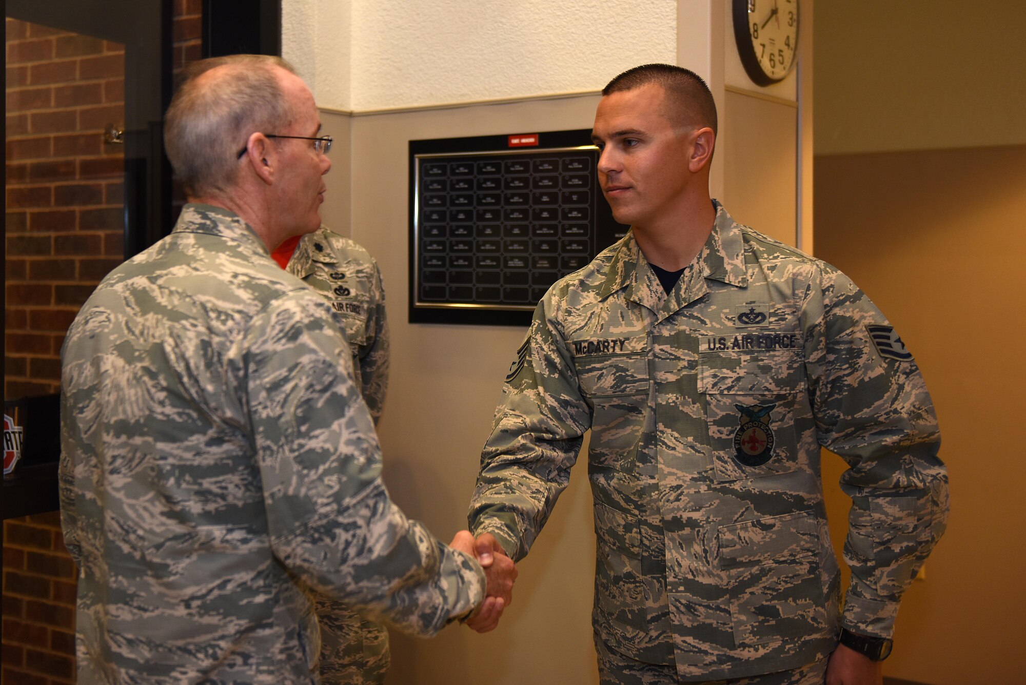 U.S. Air Force Maj. Gen. Bob LaBrutta, 2nd Air Force Commander, coins Staff Sgt. Adam McCarty, 312th Training Squadron rescue instructor, at the student dorms on Goodfellow Air Force Base, Texas, Oct. 7, 2016. McCarty was recognized for assisting emergency responders during an off-base emergency. (U.S. Air Force photo by Airman 1st Class Caelynn Ferguson/Released)