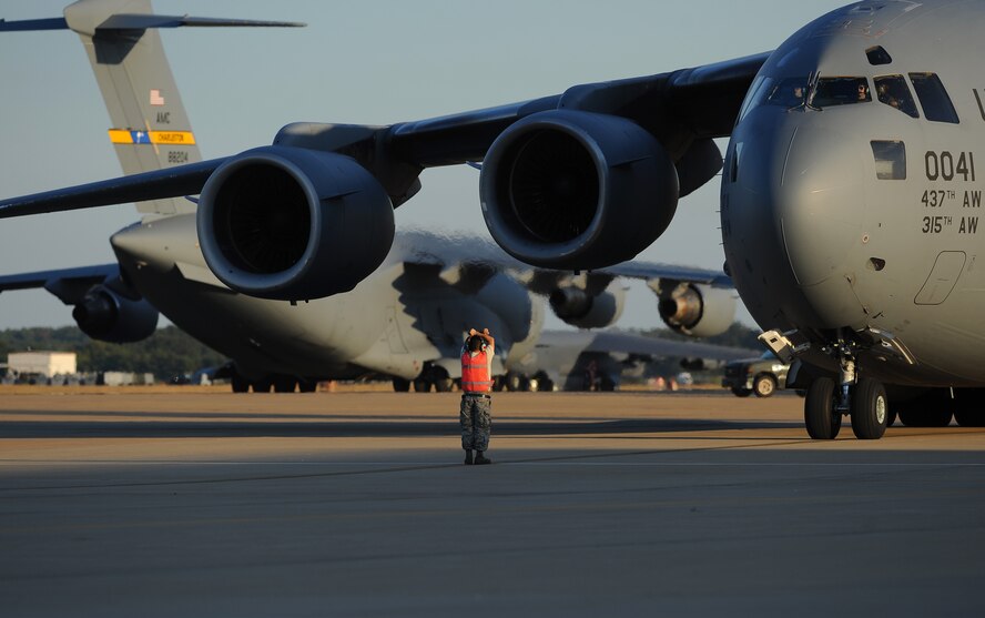 An Airman signals to the crew of a C-17 Globemaster III to stop at Barksdale Air Force Base, La., Oct. 5, 2016. More than 100 aircraft from Shaw Air Force Base, S.C., Joint Base Charelston, S.C., and Seymour Johnson Air Force Base, N.C., were relocated to avoid potential damage from Hurricane Matthew along the East Coast. (U.S. Air Force photo/Airman 1st Class Stuart Bright)