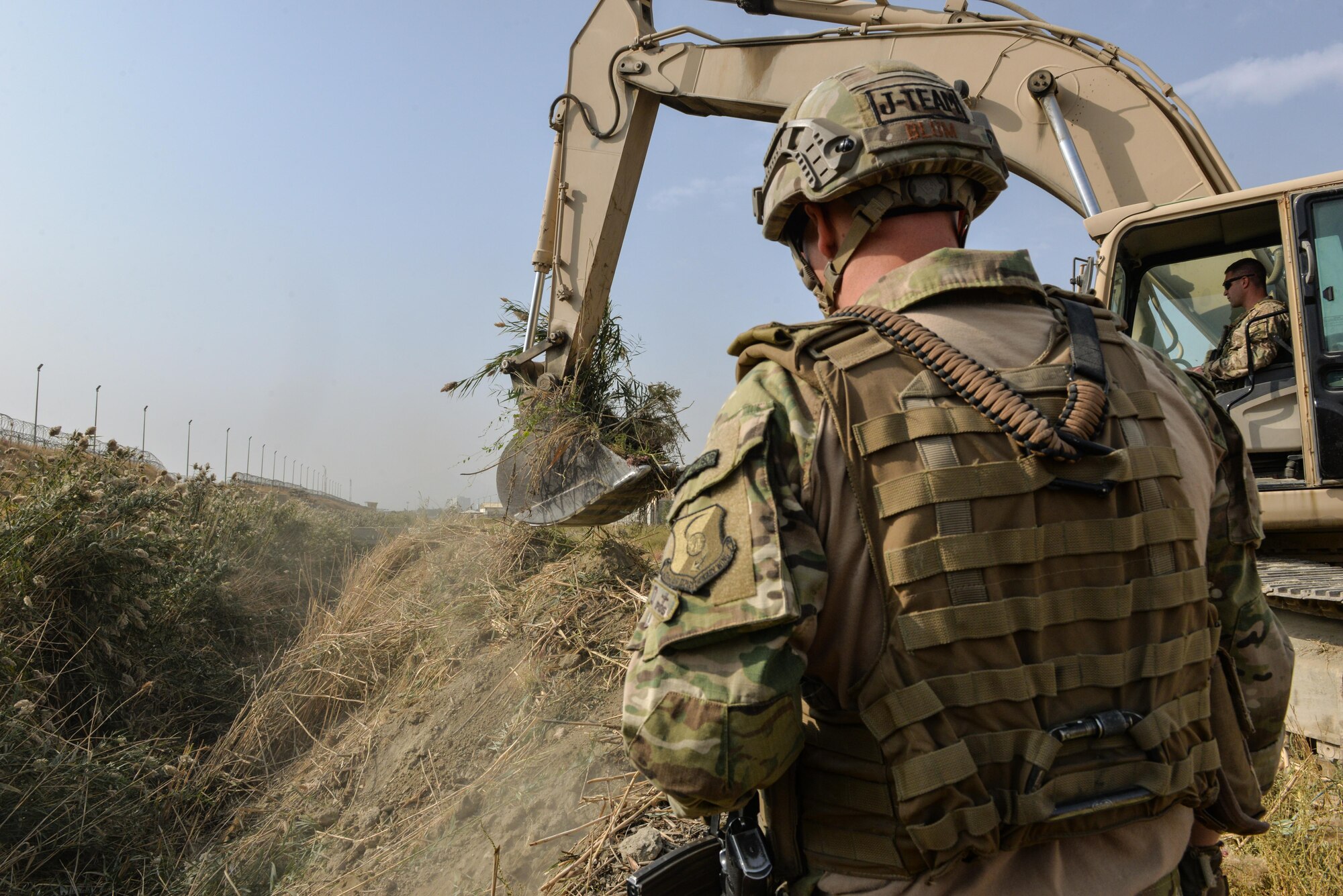 Capt. Erik Blum watches as Master Sgt. Thomas Ryan removes reeds from a 7-meter deep trench at Kabul Air Wing, Afghanistan, Oct. 6, 2016. The Train, Advise, Assist Command-Air (TAAC-Air) civil engineer advisors worked to clear a field of reeds in excess of 15-feet tall. The height of the vegetation had become a force protection concern for security forces personnel manning an entry control point who couldn't properly see past the field. (U.S. Air Force photo by Tech. Sgt. Christopher Holmes)
