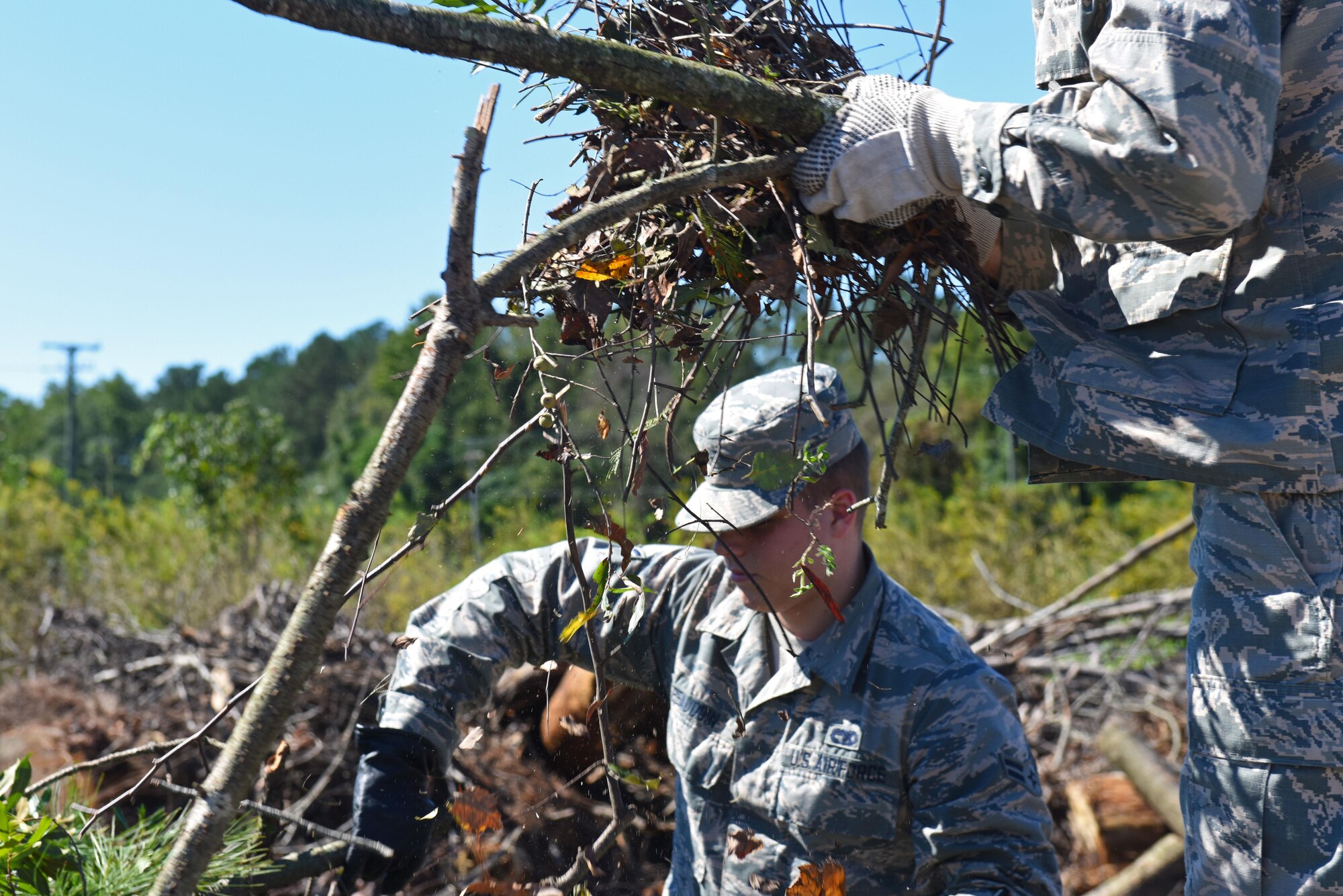 Airman 1st Class Tyan Beaudoin (center), 4th Logistics Readiness Squadron vehicle operations technician, and Airman Basic Connor Turvy (right), 4th Component Maintenance Squadron fuel systems technician, clean up the aftermath of Hurricane Matthew, Oct. 9, 2016, at Seymour Johnson Air Force Base, North Carolina. Seymour Johnson AFB Airmen cleaned up branches from the several trees that were uprooted all over base during the storm. (U.S. Air Force photo by Airman 1st Class Ashley Williamson)