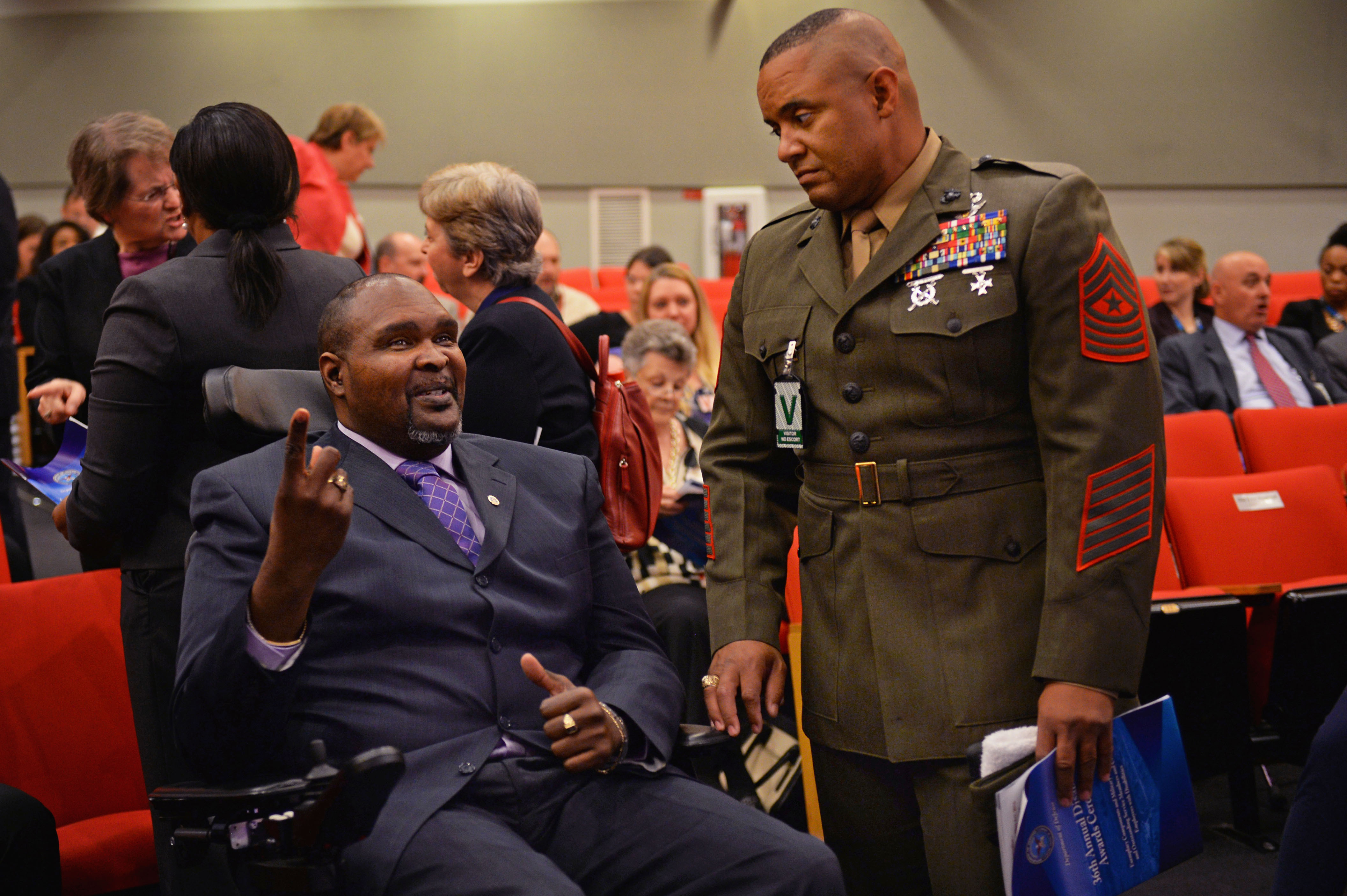 Photo of a man in a wheelchair talking to a man in a uniform