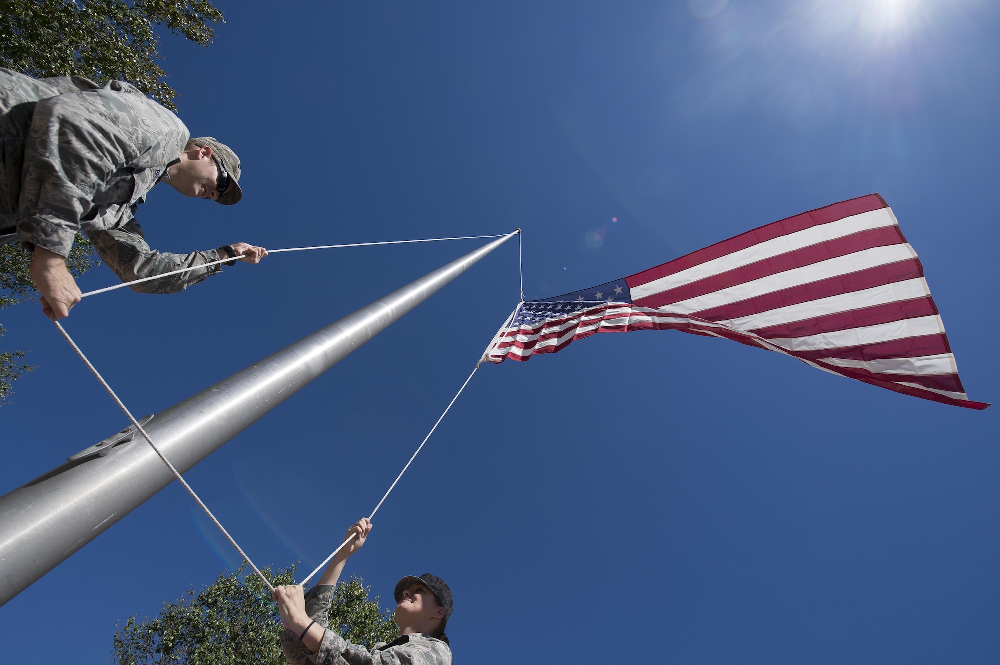 U.S. Air Force Lt. Col. Matthew Brennan, left, the commander of the 628th Civil Engineer Squadron, and Maj. Abbillyn Johnson, the commander of the 628th Logistics Readiness Squadron, raise the base flag over Joint Base Charleston, S.C., after Hurricane Matthew swept the area Oct. 9, 2016. All non-essential personnel evacuated the area, but returned after disaster response coordinators assessed damage and verified a safe operating environment.