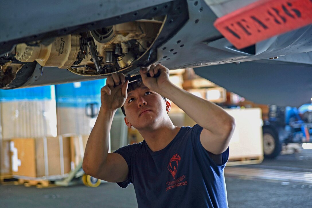 Navy Seaman Tae Lee trims worn fip seal from an F/A-18E Super Hornet in the hangar bay of the aircraft carrier USS Dwight D. Eisenhower in the Persian Gulf, Oct. 8, 2016. Navy photo by Seaman Christopher A. Michaels