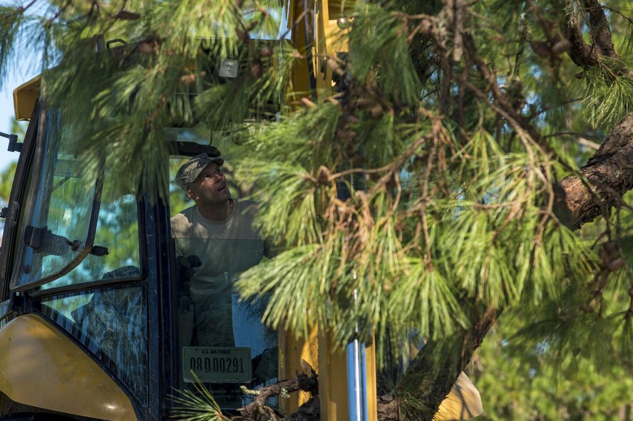 U.S. Air Force Master Sgt. Chris Moffett,  heavy equipment operator with the 628th Civil Engineer Squadron, tears down a broken tree limb after  Hurricane Mathew swept through Joint Base Charleston, S.C., Oct. 9, 2016. All non-essential personnel evacuated the area, but returned after disaster response coordinators assessed damage and verified a safe operating environment.