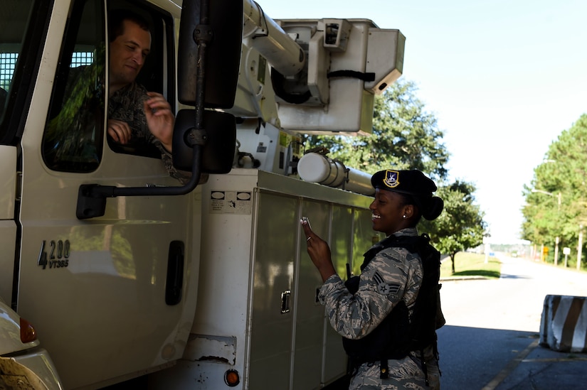 U.S. Air Force Senior Airman Jasmine Jamison, a patrol officer with the 628th Security Forces Squadron, checks the identification of those entering the gates after Hurricane Matthew swept the area on Joint Base Charleston - Naval Weapons Station, S.C., Oct. 9, 2016. All non-essential personnel evacuated the area, but returned after disaster response coordinators assessed damage and verified a safe operating environment. 