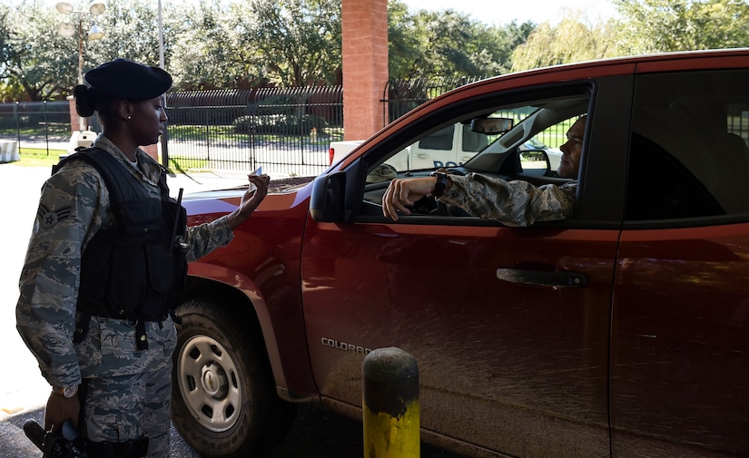 U.S. Air Force Senior Airman Jasmine Jamison, a patrol officer with the 628th Security Forces Squadron, checks the identification of those entering the gates after Hurricane Matthew swept the area on Joint Base Charleston - Naval Weapons Station, S.C., Oct. 9, 2016. All non-essential personnel evacuated the area, but returned after disaster response coordinators assessed damage and verified a safe operating environment. 