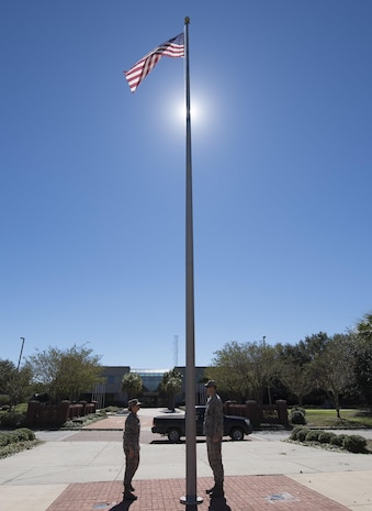 U.S. Air Force Maj. Abbillyn Johnson, left, the commander of the 628th Logistics Readiness Squadron, and Lt. Col. Matthew Brennan, the commander of the 628th Civil Engineer Squadron, raise the base flag over Joint Base Charleston, S.C., after Hurricane Matthew swept the area Oct. 9, 2016. All non-essential personnel evacuated the area, but returned after disaster response coordinators assessed damage and verified a safe operating environment. 