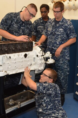 Seaman Jacob Pruett (top left), Petty Officer 3rd Class Raquel Alvarado, Petty Officer 1st Class Gregory Hermann and Petty Officer 1st Class Robin Mosely (bottom center) glide the number 1 piston into the engine block of a marine diesel engine at SERMC. Enginemen at SERMC provide engineering and technical services for maintenance and modernation of naval ships and craft in the 4th Fleet area of responsibility.