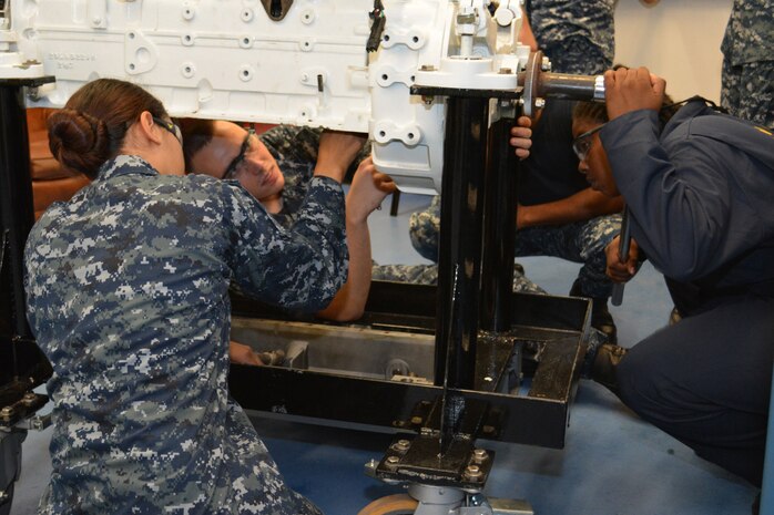 Petty Officer 1st Class Staci Allen (Right) slowly turns the crankshaft as Seaman Jacob Pruitt (Center) and Seaman Hannah Ybarra check the clearance inside the cylinder on a marine diesel engine. Sailors in the Diesel Shop at SERMC repair or replace valves, pumps, compressors and control devices used with diesel engines.