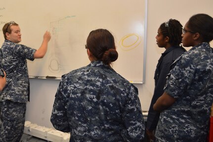 Petty Officer 1st Class Robin Mosely (left) questions (left to right) Seaman Hannah Ybarra, Petty Officer 1st Class Staci Allen and Petty Officer 3rd Class Raquel Alvarado on the different parts of a Cummins marine diesel engine at SERMC. Once trained, Sailors at SERMC clean, lubricate, adjust test and perform preventive maintenance on diesel engines.