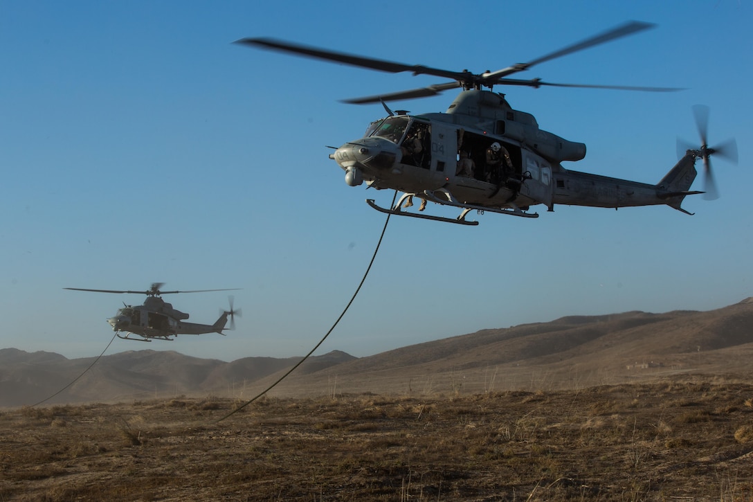 Two UH-1Y Hueys with Marine Light Attack Helicopter Squadron (HMLA) 369 hover above the ground while Marines with 1st Reconnaissance Battalion, 1st Marine Division, conduct fast-rope training aboard Marine Corps Base Camp Pendleton, Calif., Oct. 3.  Fast roping was part of a larger event called a Marine Air-Ground Task Force integration exercise, which enabled air and ground units to come together and cooperate in various training missions prior to their deployment with the 15th Marine Expeditionary Unit. (U.S. Marine Corps photo by Sgt. Lillian Stephens/Released)