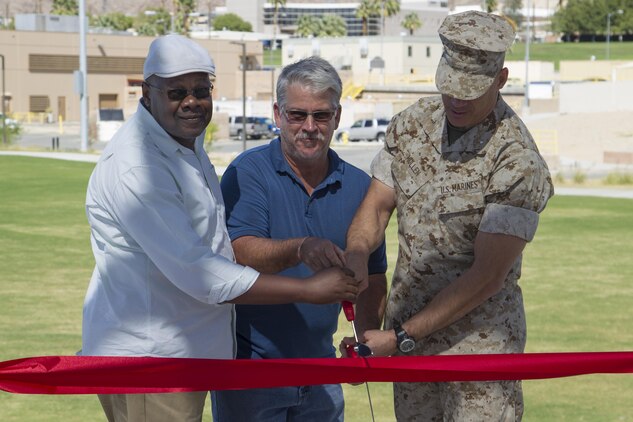 Brig. Gen. William F. Mullen III, Combat Center Commanding General, cuts the ribbon to officially open Victory Park alongside Richard Bass, superintendent, T.B. Penick and Sons, and Melvin Pickens, lead facilities management specialist, Public Works Division, aboard Marine Corps Air Ground Combat Center, Twentynine Palms, Calif., Oct. 5, 2016. (Official Marine Corps photo by Cpl. Connor Hancock/Released)