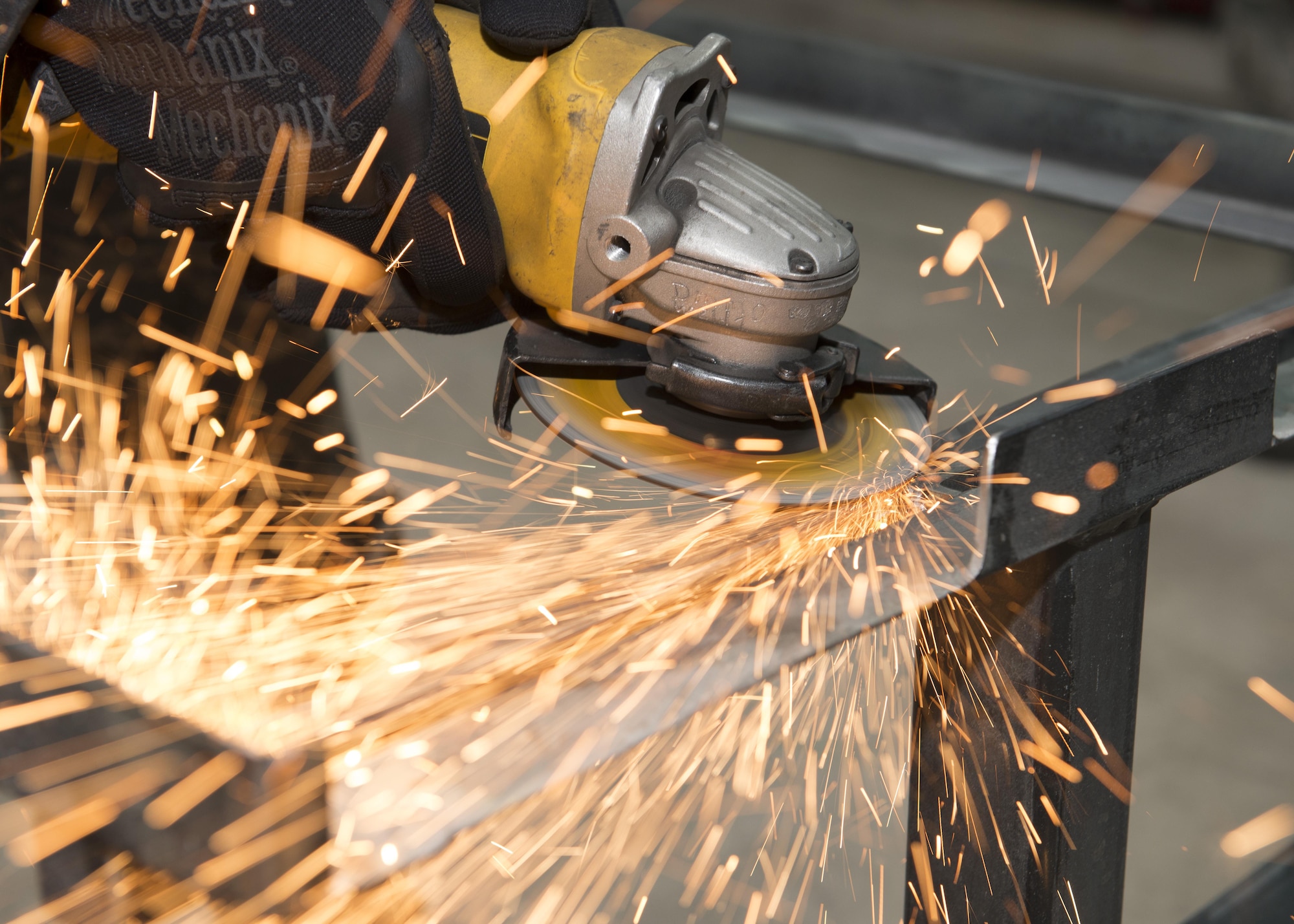 Senior Airman Cory Swan, 512th Maintenance Squadron metals technician, uses an angle grinder to remove a piece of metal from a metal frame Sept. 19, 2016, at Dover Air Force Base, Del. This frame was designed and fabricated specifically for Air Force Mortuary Affairs Operations transfer vehicles to carry transfer cases. (U.S. Air Force photo by Senior Airman Zachary Cacicia)