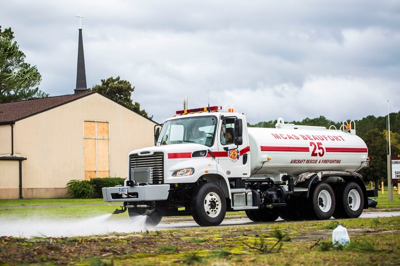 A truck sprays water to clear debris from a main road aboard Marine Corps Air Station Beaufort Oct. 8. Marines and sailors with MCAS Beaufort worked to return the air station and Laurel Bay to normal operations. They removed debris and cleaned up main access roads to establish infrastructure after Hurricane Matthew.