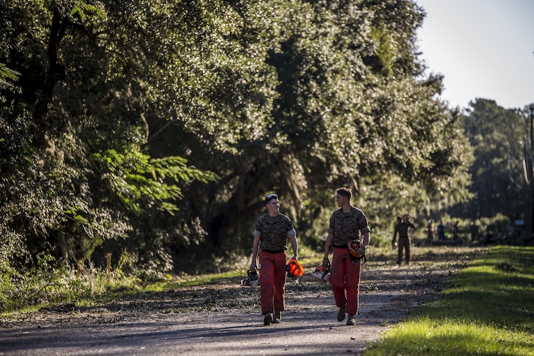 Marines carry equipment and gear after cutting down trees on a road aboard Marine Corps Air Station Beaufort Oct. 9. Marines and sailors with MCAS Beaufort continued to work to remove debris and establish infrastructure aboard the air station and Laurel Bay after Hurricane Matthew. 