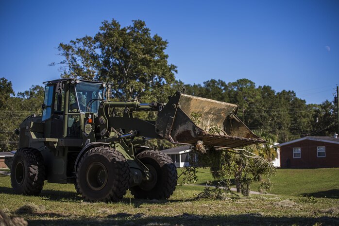 A Marine uses heavy equipment to remove a fallen tree from a backyard aboard Laure Bay Oct. 9. Marines and sailors with Marine Corps Air Station Beaufort continued to work to remove debris and establish infrastructure aboard the air station and Laurel Bay after Hurricane Matthew. 