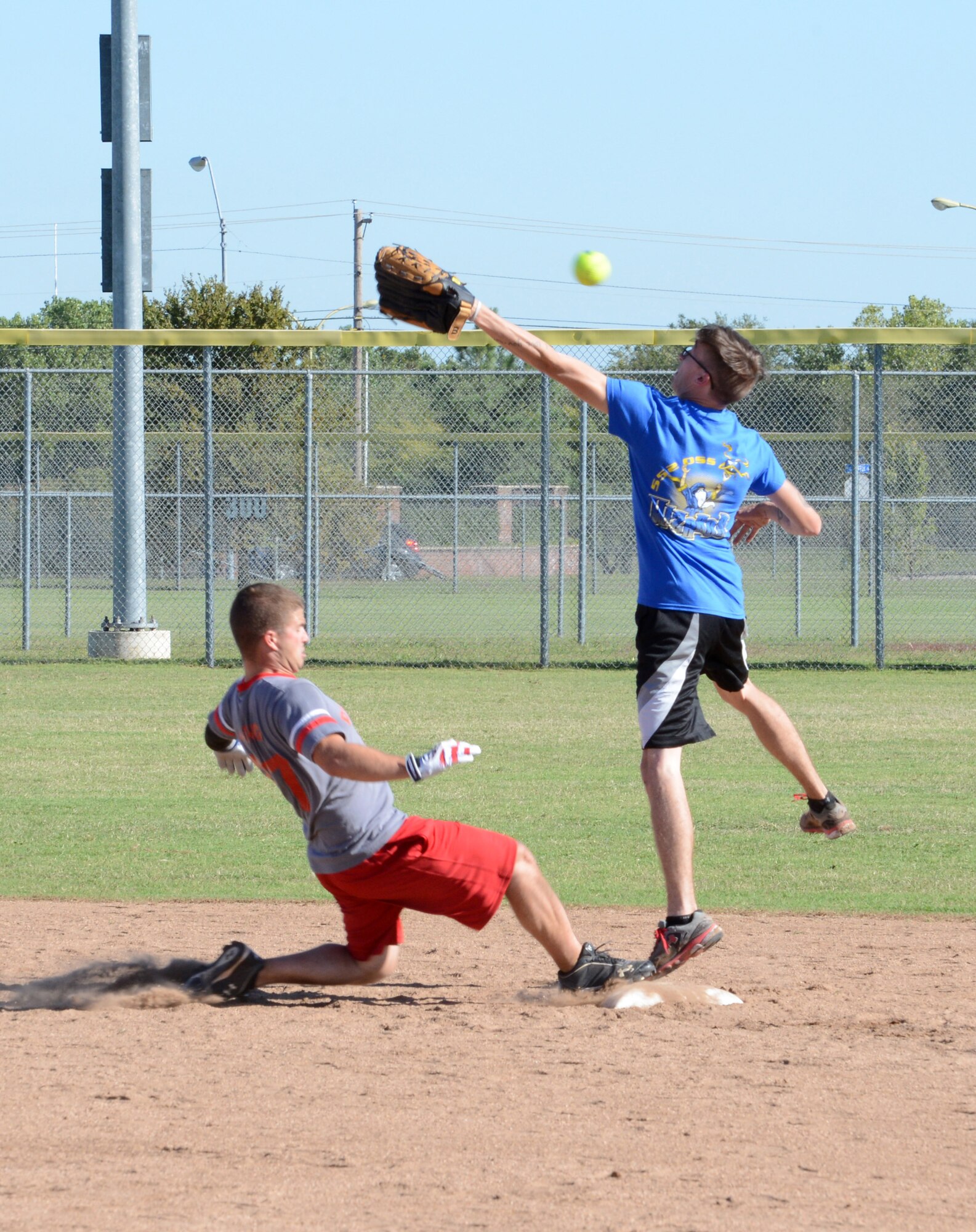 Staff Sgt. Justin Laing, with the 552nd Maintenance Group’s Aerospace Ground Equipment shop, slides safely into second base as Senior Airman Tyler Starr, with the 72nd Operations Support Squadron’s softball team, barely misses a long throw from the outfield. (Air Force photo by Kelly White)
