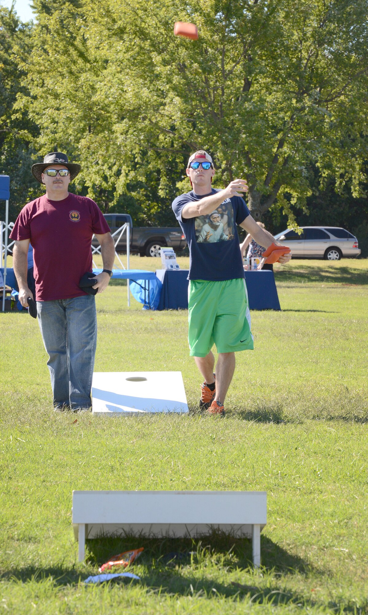Airman 1st Class Eric Huster, with the 966th Airborne Air Control Squadron, tosses his bag, while Sgt. Christopher Merlin, with the 964th AACS, waits for his turn while playing in the cornhole tournament. (Air Force photo by Kelly White)
