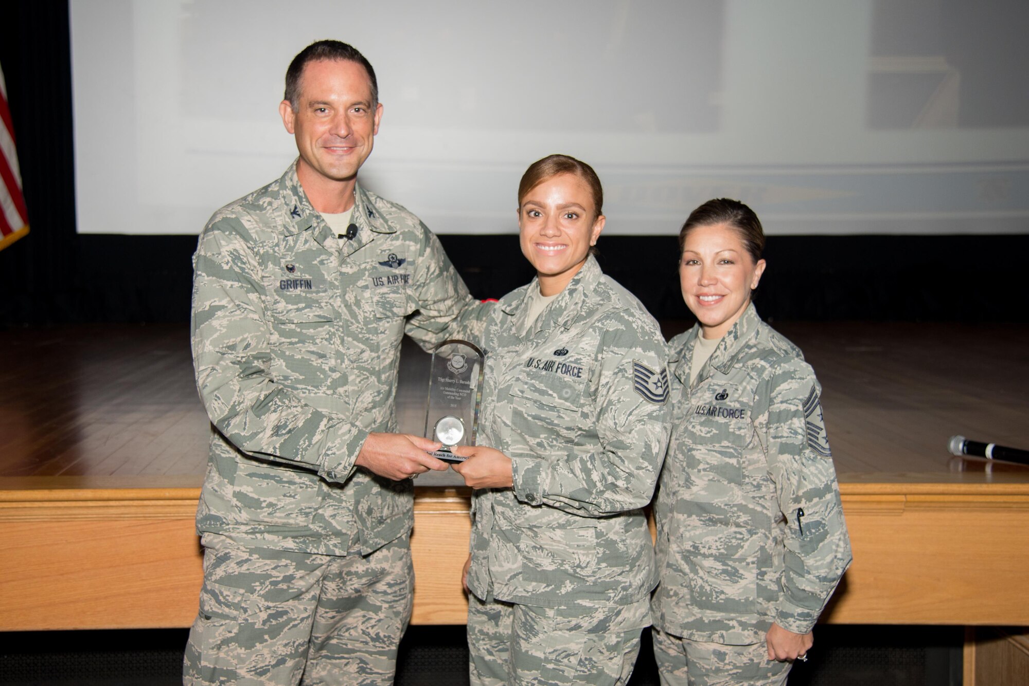 Col. Ethan Griffin, 436th Airlift Wing commander, and Chief Master Sgt. Sarah Sparks, 436th Airlift Wing command chief, present the Air Mobility Command NCO of the Year Award to Tech. Sgt. Sharry Barnshaw, 436th Communications Squadron client systems section chief, during a commander’s call Oct. 5, 2016, at Dover Air Force Base, Del. Barnshaw was selected as one of the Air Force 12 Outstanding Airmen of 2016. (U.S. Air Force photo by Mauricio Campino)