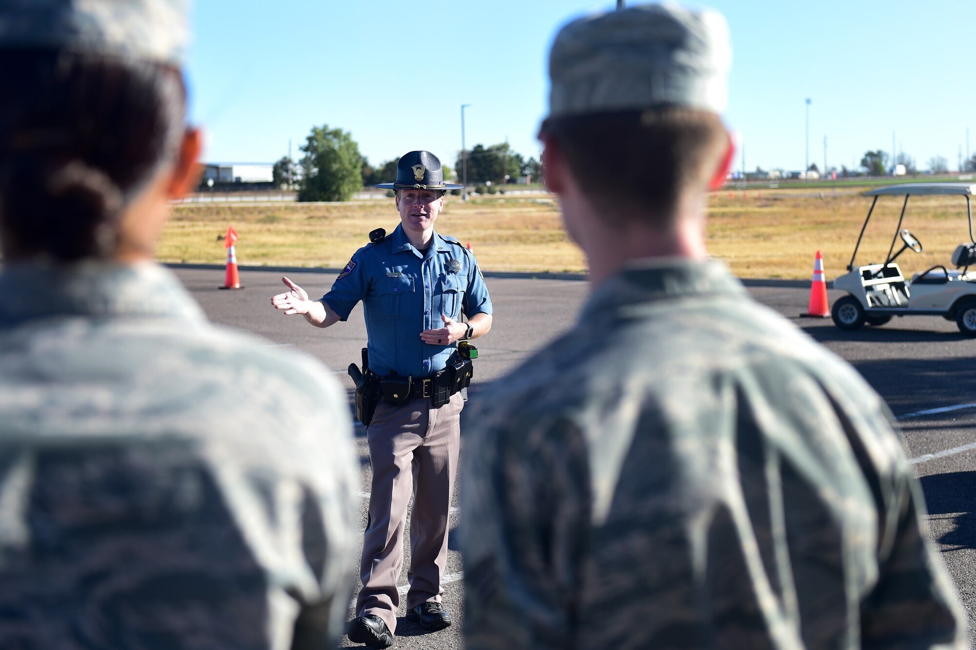 Josh Lewis, Colorado State Trooper, explains the process of a field sobriety test to Team Buckley members during a Safety Day event Oct. 7, 2016, at the fitness center on Buckley Air Force Base, Colo. The hands-on portions of the event included four alcohol-impairment obstacles courses, two field sobriety stations, child seat safety station, motorcycle safety station, experienced driver station, marijuana impairment station, semi-truck blind spot demonstration, a wrecked car from a DUI, and a hunting and outdoor station. (U.S. Air Force photo by Airman 1st Class Gabrielle Spradling/Released)