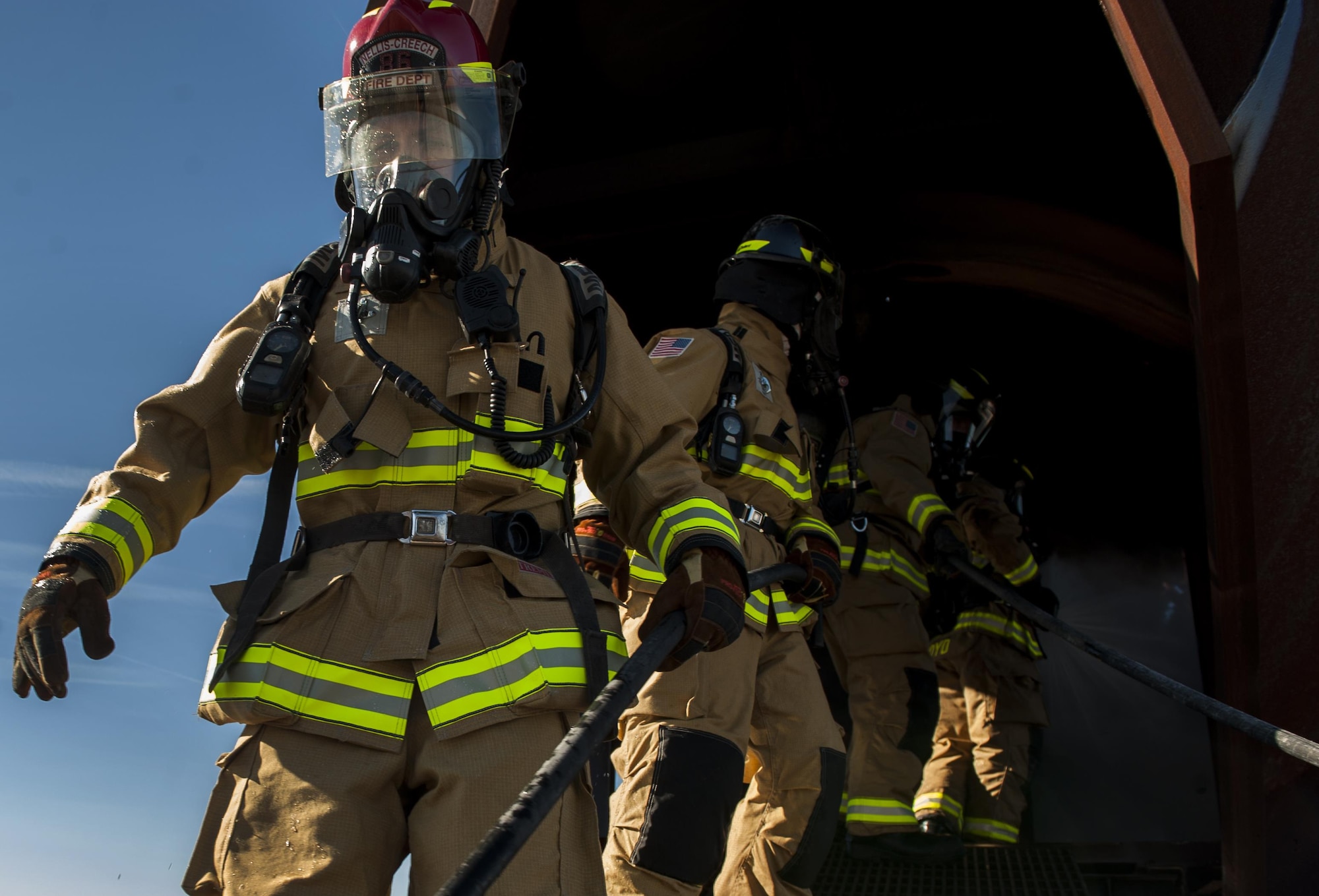 Firefighters, assigned to the 99th Civil Engineer Squadron Fire Protection Flight, exit a mock shell of an aircraft after putting out controlled fires at Nellis Air Force Base, Nev., Oct. 6, 2016. On Wednesday, Oct. 12, NCFD will be at the Child Development Centers from 9 a.m. to 10:30 a.m. with a Fire Truck and Sparky the Fire Dog. (U.S. Air Force photo by Airman 1st Class Kevin Tanenbaum/Released)