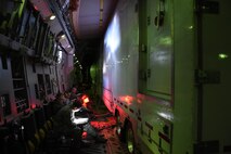 The 4th Space Operations Squadron mobile team rests on the outskirts of the Advanced Ground Mobile space operating semitrailer aboard a C-17 Globemaster III during a flight to their Hawaii operating location. The AGM needed to be tightly and safely secured with chains and homemade wooden support dunnage for the overseas flight. (U.S. Air Force photo/2nd Lt. Darren Domingo)