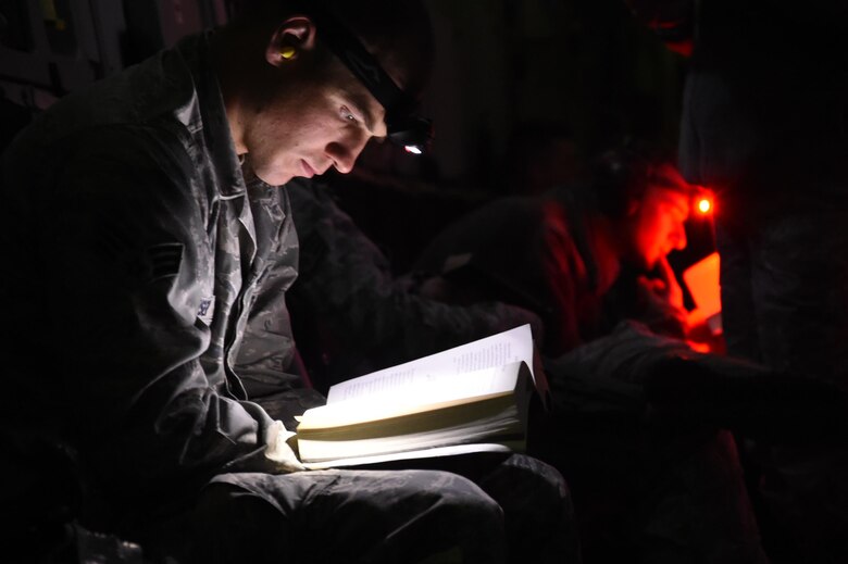 Senior Airman Hans Houser, 4th Space Operations Squadron mobile Extremely High Frequency satellite operator and weapons manager, reads aboard a C-17 Globemaster III during a flight to their Hawaii operating location. The team executed a rare mobile space operating contingency mission in a peacetime environment outside the continental United States. (U.S. Air Force photo/2nd Lt. Darren Domingo)