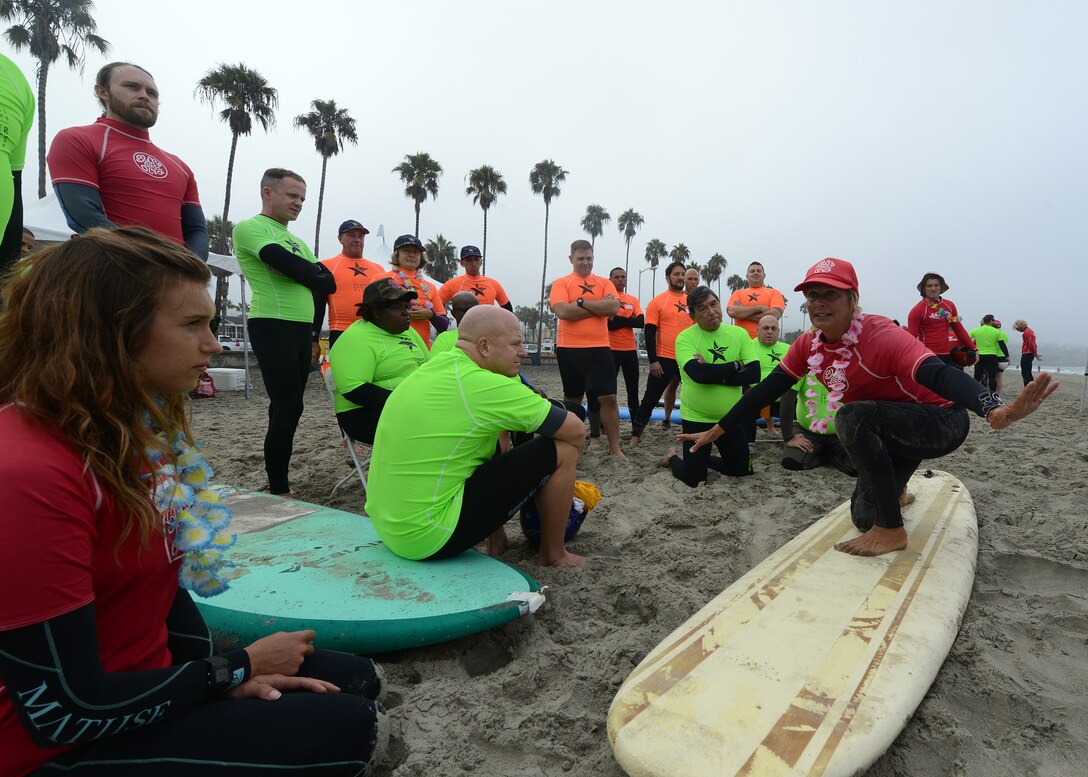 A surf instructor shows the veterans how to properly stand up on a surfboard during the National Disabled Veterans Summer Sports ClinicSept. 19, 2016 at San Diego, Ca. The clinic gave veterans an opportunity to challenge themselves through education and recreational activities. Rehabilitation was promoted using summer sporting activities such as surfing, archery, sailing, kayaking, cycling and rowing. 
(U.S. Air Force photo by Senior Airman Devante Williams)