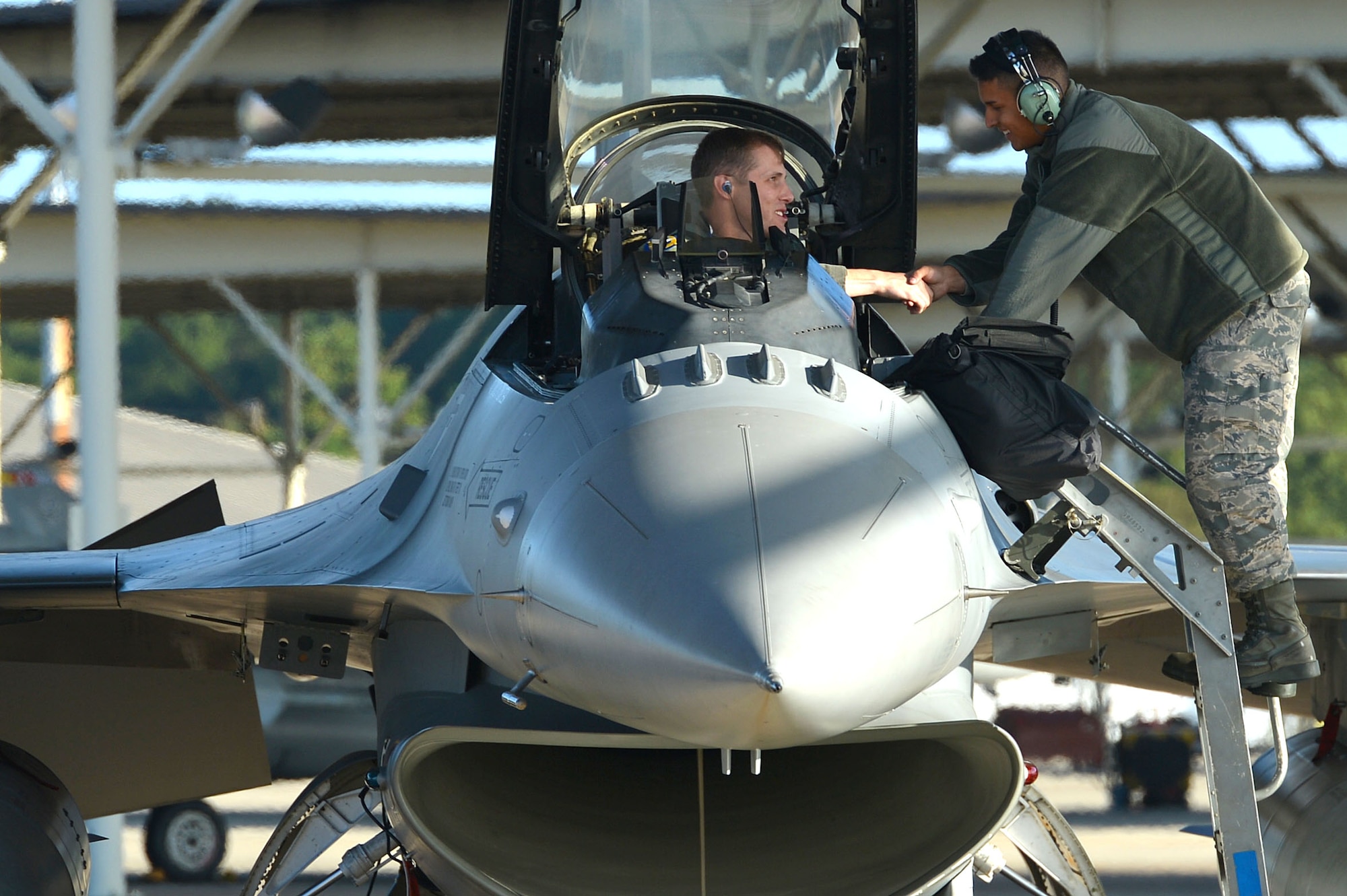 An F-16CM Fighting Falcon pilot assigned to the 20th Fighter Wing shakes hands with a tactical aircraft maintainer assigned to the 20th Aircraft Maintenance Squadron during an aircraft evacuation at Shaw Air Force Base, S.C., Oct. 6, 2016. Forty-eight F-16s were evacuated from Shaw in anticipation of Hurricane Matthew, which hit South Carolina as a Category 2 hurricane. (U.S. Air Force photo by Airman 1st Class Christopher Maldonado)