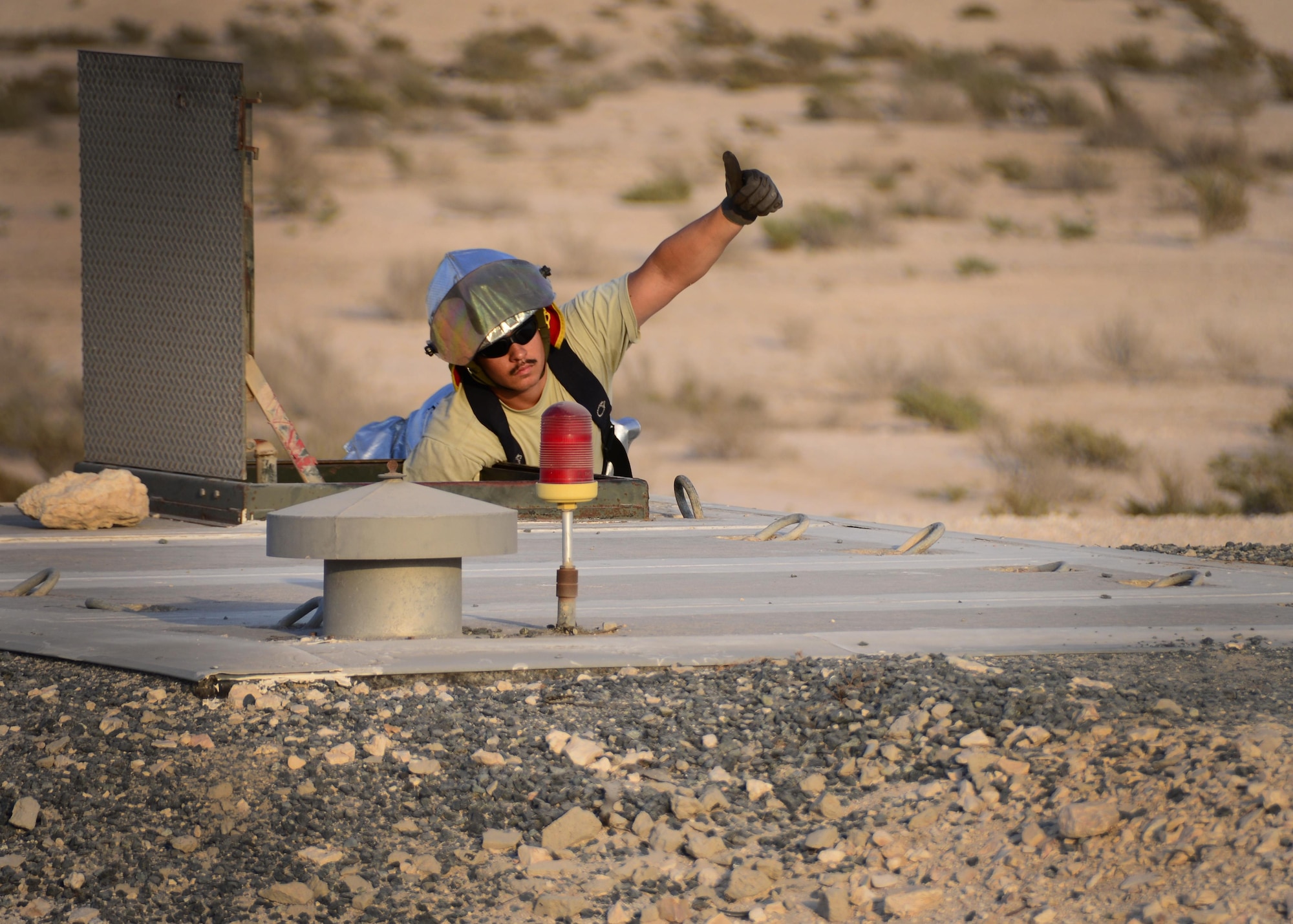 Staff Sgt. Thomas Cabalo, 379th Expeditionary Civil Engineer Squadron firefighter, signals to Airmen inside of the Barrier Arresting Kit-12 to wind up the Aircraft Arresting System Oct. 9, 2016, at Al Udeid Air Base, Qatar. The BAK-12 system works in conjunction with a tensioned cable, known as the pendant, and the BAK-14, a system that raises and lowers the cable as needed. (U.S. Air Force photo/Senior Airman Miles Wilson/Released)