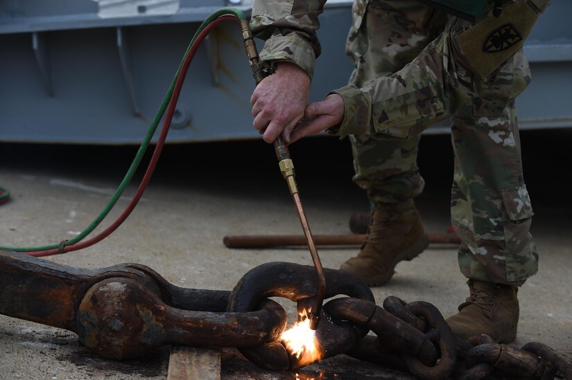 U.S. Army Staff Sgt. Jessy Kingrey, 558th Transporation Company maintenance control sergeant, uses a non-cutting torch to loosen a cast iron anchor from a U.S. Army vessel at Joint Base Langley-Eustis, Va., Oct. 7, 2016. The anchor was removed to move the vessel to hurricane buoys, which is where vessels with crew shortages and in maintenance were transferred during Hurricane Matthew. (U.S. Air Force photo by Staff Sgt. Natasha Stannard)