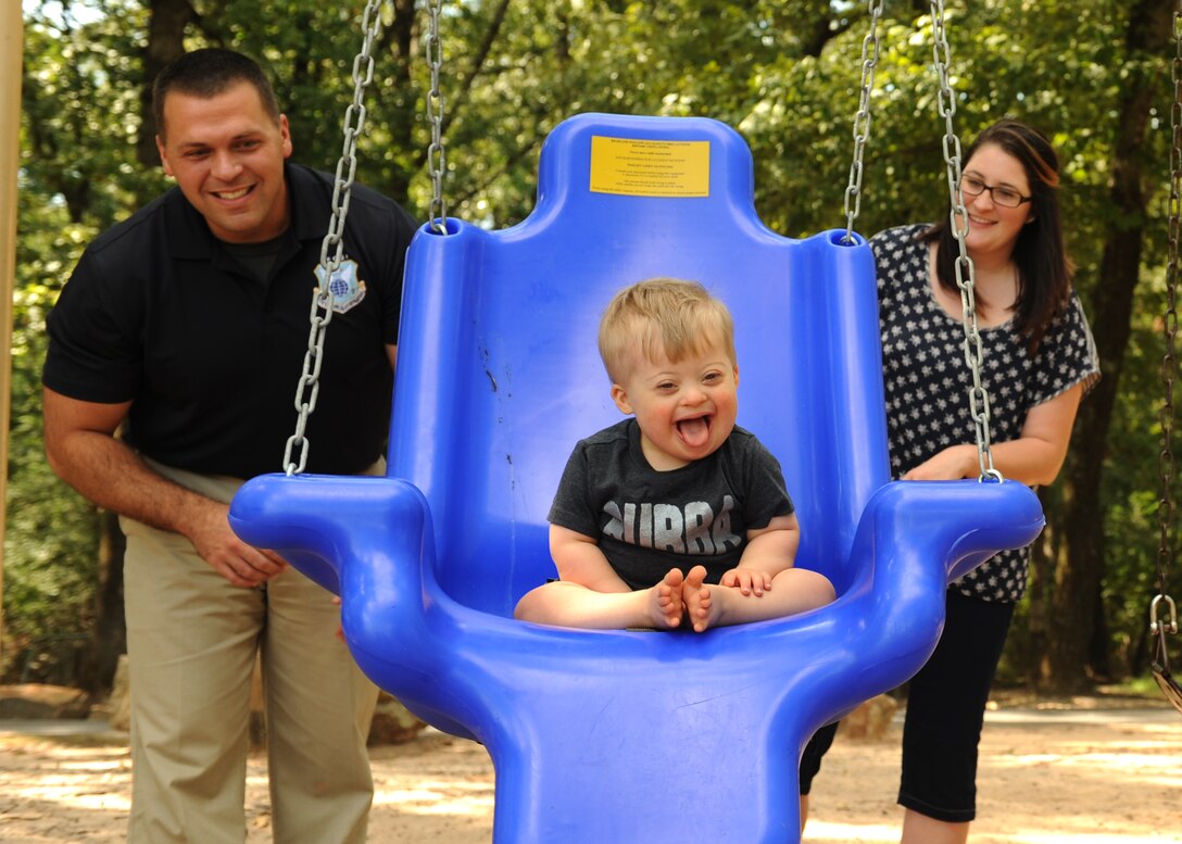 U.S. Air Force Special Agent Adam Boccher and Brittany Boccher push their son, Blake, in a swing, Sept. 9, 2016, at Little Rock Air Force Base, Ark. The accessible therapeutic swing was unveiled at the playground near the Family Camp and small base lake by the base Exceptional Family Member Program. 