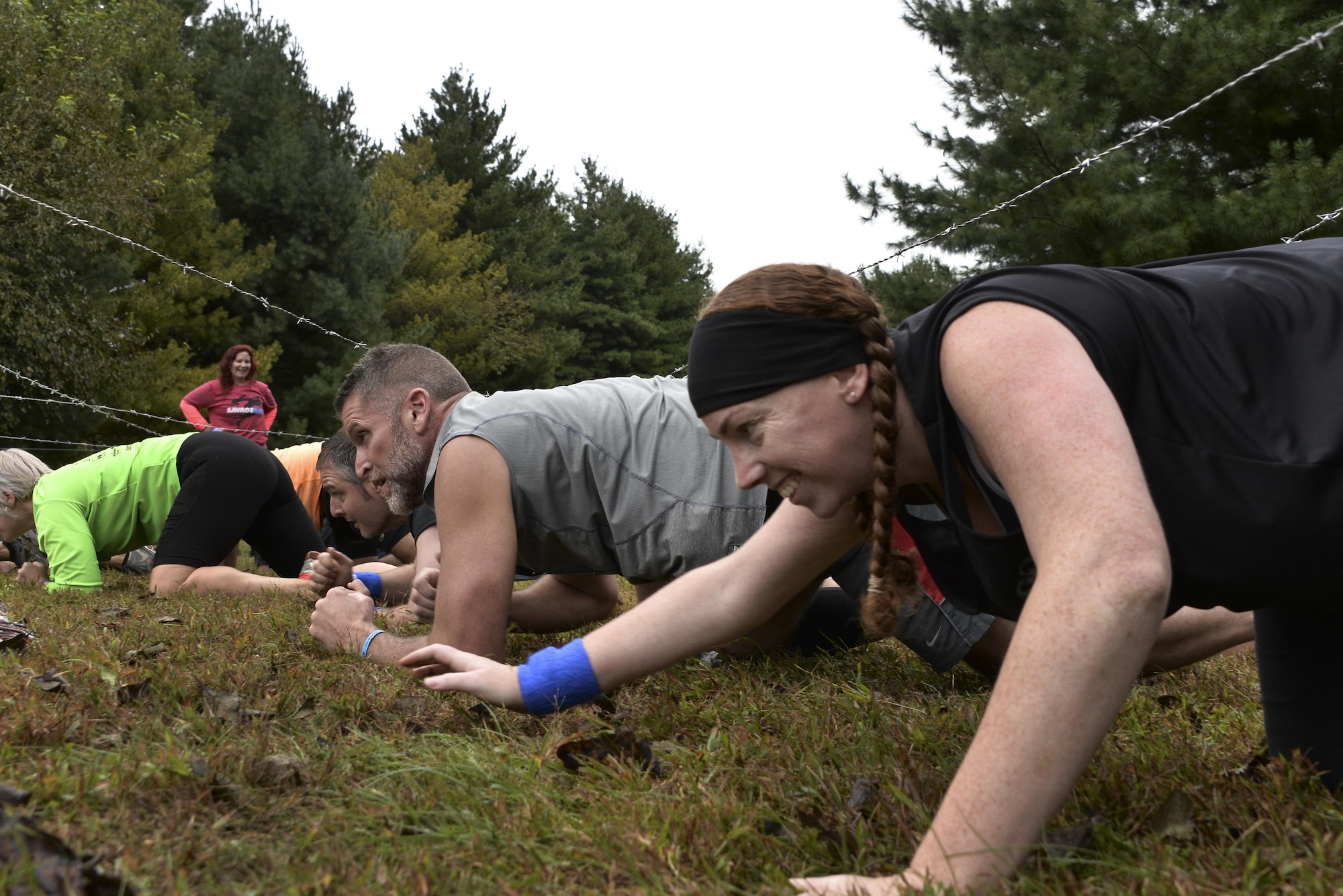 Meghan Root, 70th Intelligence, Surveillance and Reconnaissance Wing Sexual Assault Response Coordinator, low-crawls under barbed wire during the 2016 Savage Race October 8, 2016 at Kennedyville, Md. 70th ISRW participants endured a seven-mile obstacle course of cargo net walls, creeks, ice cold water and climbing to test their stamina and strength as a team. (U.S. Air Force photo/Staff Sgt. Alexandre Montes)