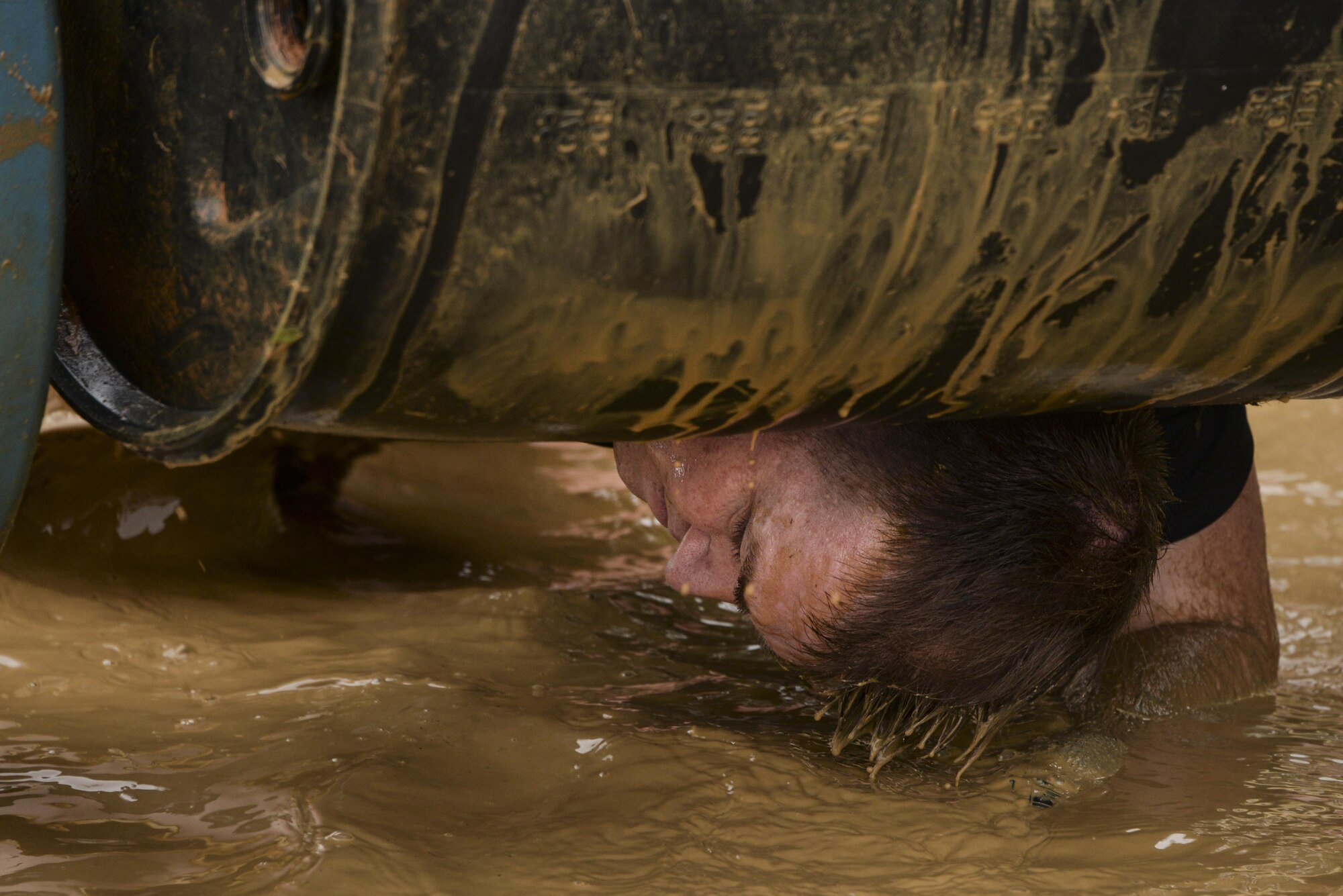 Lt. Col. Mark Betters, 70th Intelligence, Surveillance and Reconnaissance Wing cyberspace integration director, passes under a weighted drum that is submerged in muddy water during the 2016 Savage Race October 8, 2016 at Kennedyville, Md. 70th ISRW participants endured a seven-mile obstacle course of cargo net walls, creeks, ice cold water and climbing to test their stamina and strength as a team. (U.S. Air Force photo/Staff Sgt. Alexandre Montes)