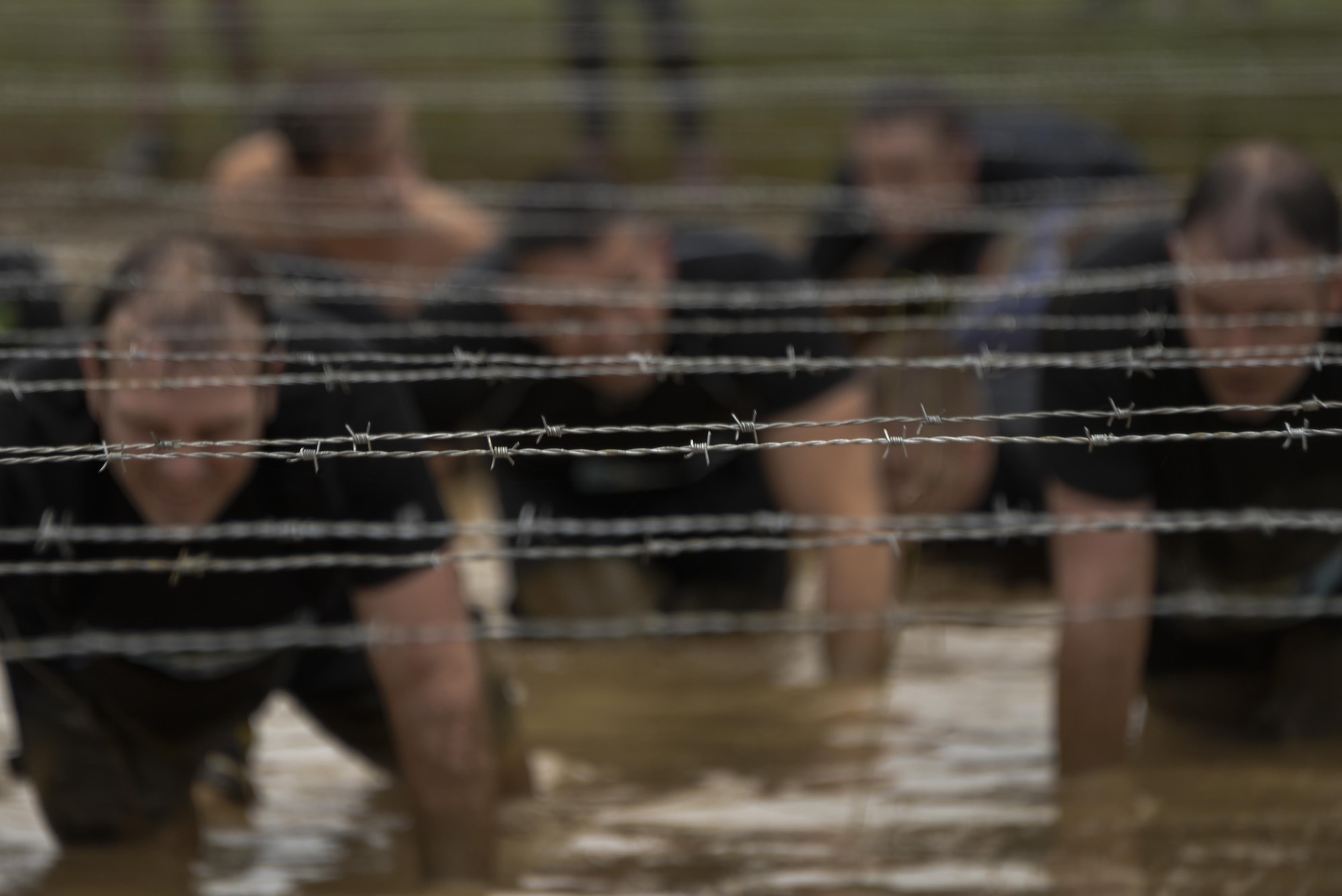 Airmen from the 70th Intelligence, Surveillance and Reconnaissance Wing crawl through mud under rows of barbed wire during the 2016 Savage Race October 8, 2016 at Kennedyville, Md. 70th ISRW participants endured a seven-mile obstacle course of cargo net walls, creeks, ice cold water and climbing to test their stamina and strength as a team. (U.S. Air Force photo/Staff Sgt. Alexandre Montes)