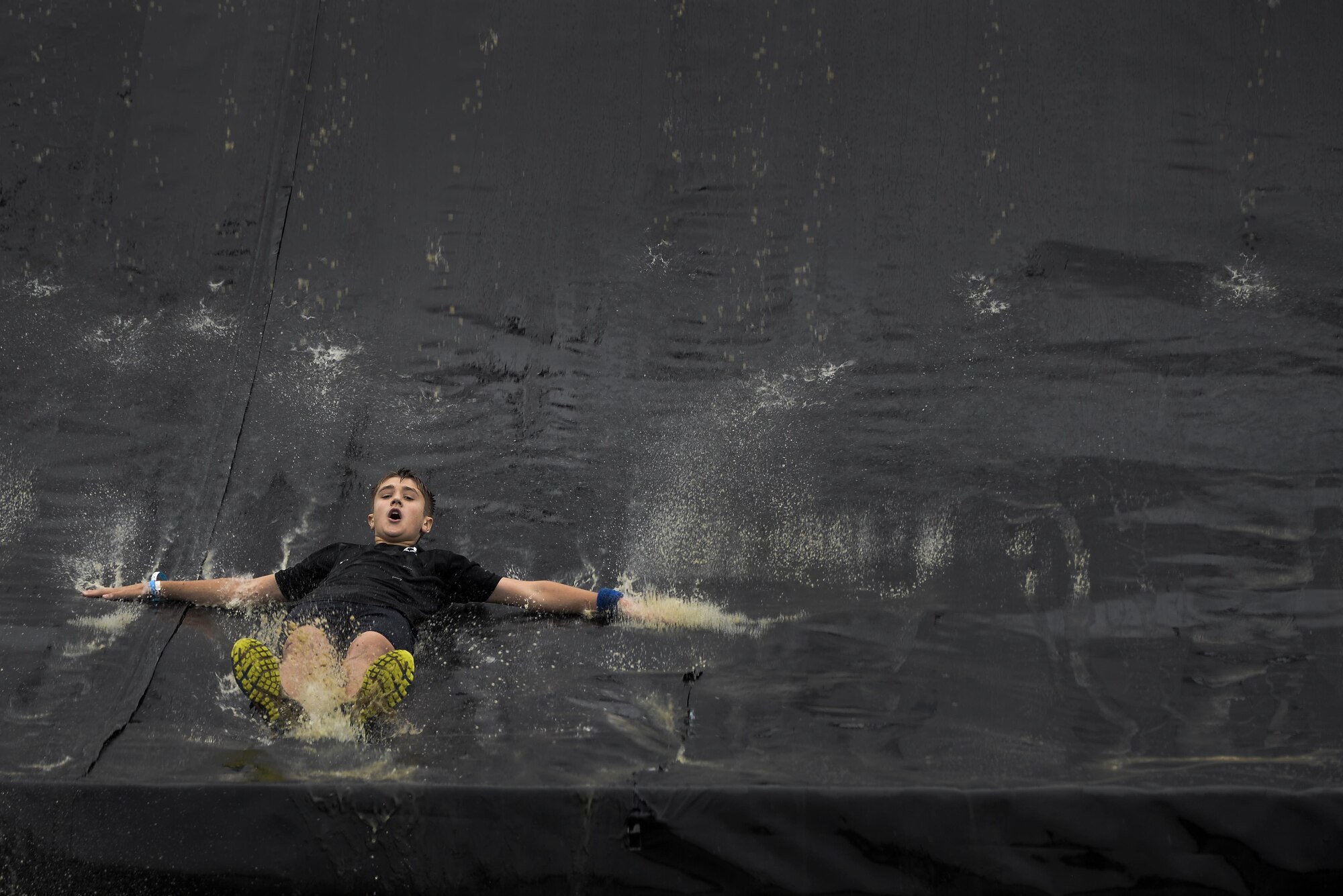 Grant Gillinger slides down a 43-foot water slide after completing ‘Colossus’ a 43-foot quarter pipe wall during the final stages of the 2016 Savage Race October 8, 2016 at Kennedyville, Md. 70th ISRW participants endured a seven-mile obstacle course of cargo net walls, creeks, ice cold water and climbing to test their stamina and strength as a team. (U.S. Air Force photo/Staff Sgt. Alexandre Montes)