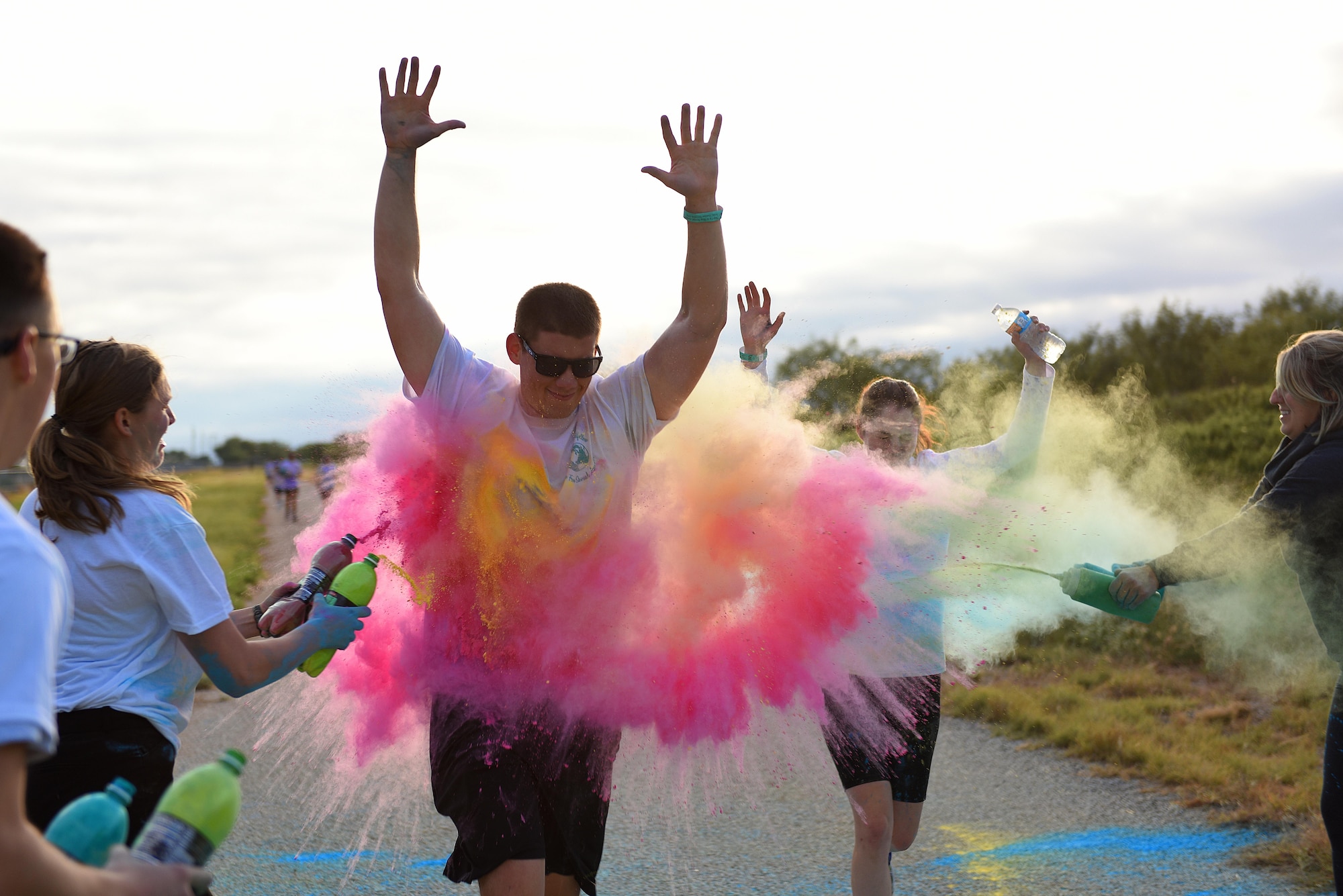 Participants during the annual Sexual Assault Prevention and Response Color Run jog through a cloud of powder color on the Kiowa Trail on Goodfellow Air Force Base, Texas, Oct. 8, 2016. Volunteers were stationed along the trail to throw colors at the participants as they ran by. (U.S. Air Force photo by Airman 1st Class Caelynn Ferguson/Released)