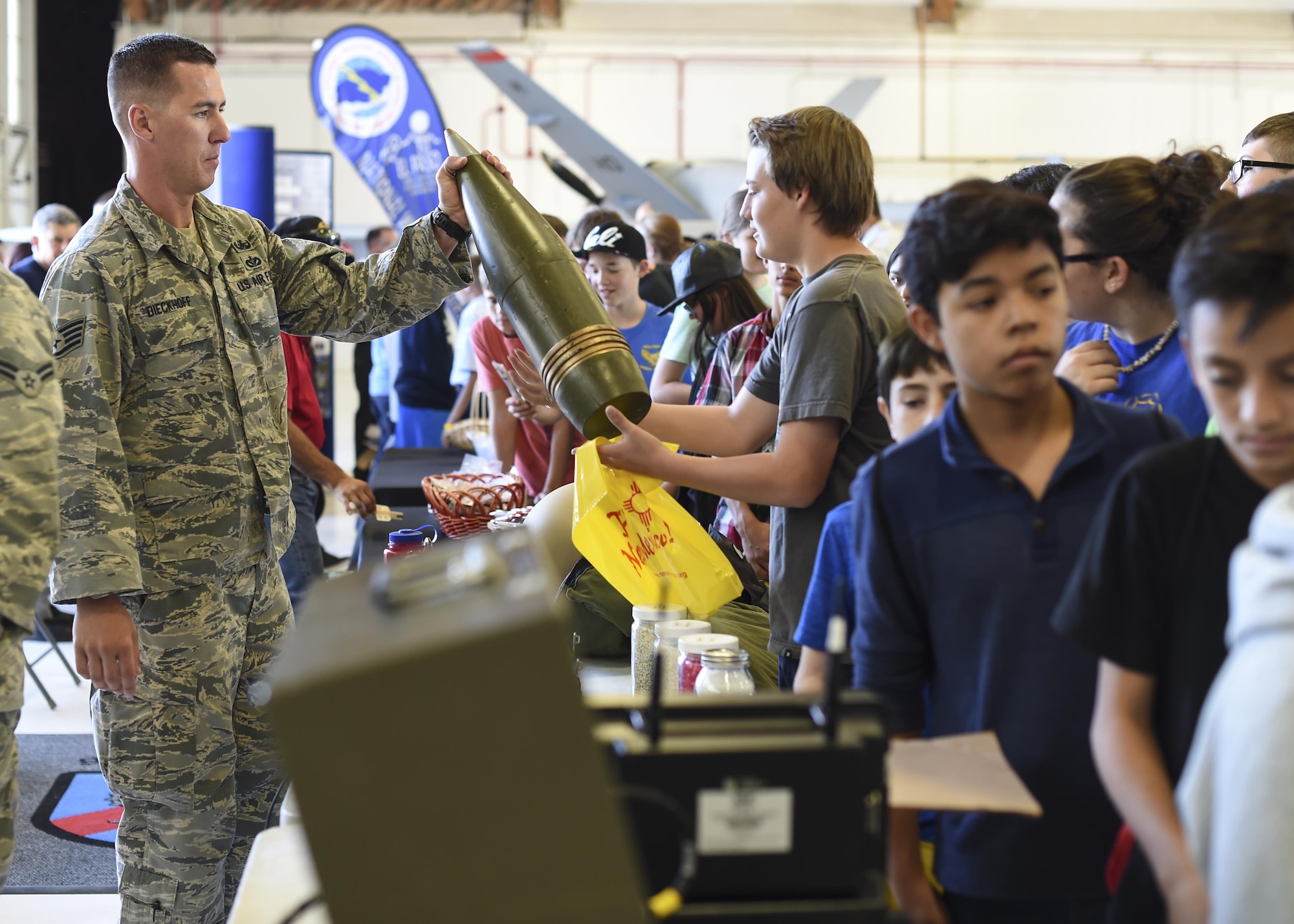 Staff Sgt. Evan Dieckhoff, Explosive Ordnance Disposal technician with 49th Civil Engineer squadron hands a a plastic training aid a mock-up of an artillery projectile to a student during the fourth annual New Mexico Aviation Aerospace Association Career Expo Oct. 6, 2016 at Holloman Air Force Base N.M. About 2,500 middle school through college-level students from across New Mexico came out to learn about the science, technology, engineering and mathematics fields. The goal of STEM is to motivate and educate students by giving them a taste of what aviation and aerospace engineering is all about. These STEM events also get the students talking to people who are working directly in STEM industries.  (U.S. Air Force photo by Staff Sgt. Stacy Jonsgaard)