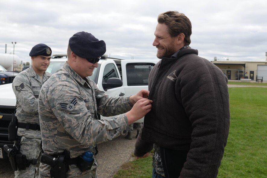 Senior Airman Dakota Willis, 5th Security Forces Squadron military working dog handler, adjusts a bite suit on country artist Chase Rice at Minot Air Force Base, N.D., Oct. 8, 2016. Rice and his crew participated in a dog bite demonstration before a meet-and-greet with base personnel. (U.S. Air Force photo/Airman 1st Class Jessica Weissman) 