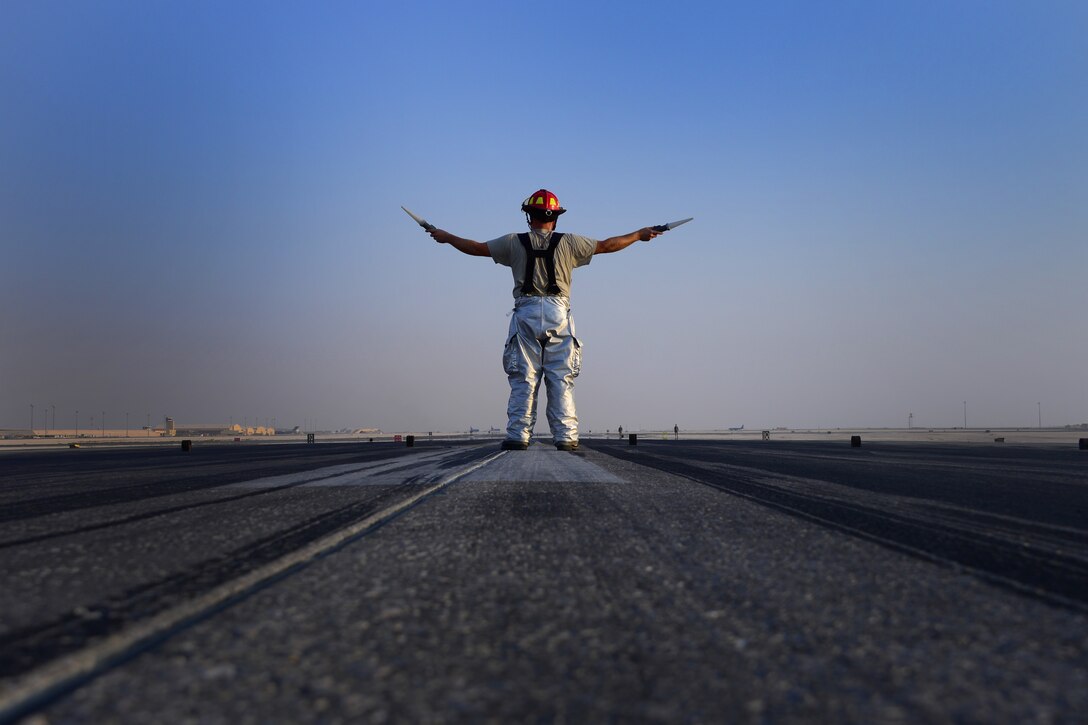 Tech. Sgt. Kris Anderson, 379th Expeditionary Civil Engineer Squadron firefighter, takes the point man position during an Aircraft Arresting System certification test Oct. 9, 2016, at Al Udeid Air Base, Qatar. The point man is responsible for signaling Airmen at the Barrier Arresting Kit-12 units to wind up the cable that catches the aircraft. The cable is wound up evenly to avoid an imbalance of tension that could cause an aircraft to veer off of the runway. (U.S. Air Force photo/Senior Airman Miles Wilson/Released)